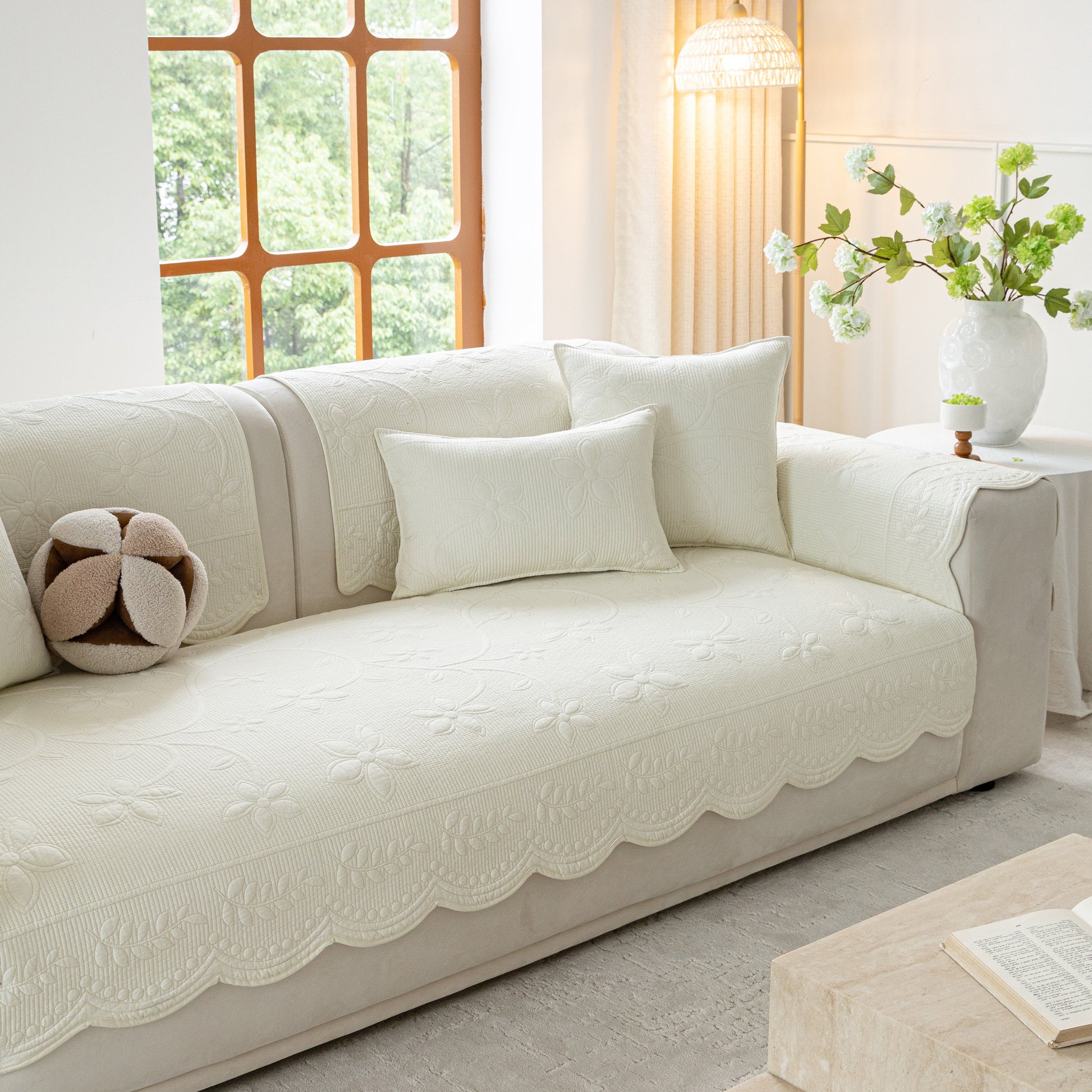 Floral Cotton Quilted Sofa Cover, Non-Slip Couch Protector with Scalloped Edges on white couch in living room.