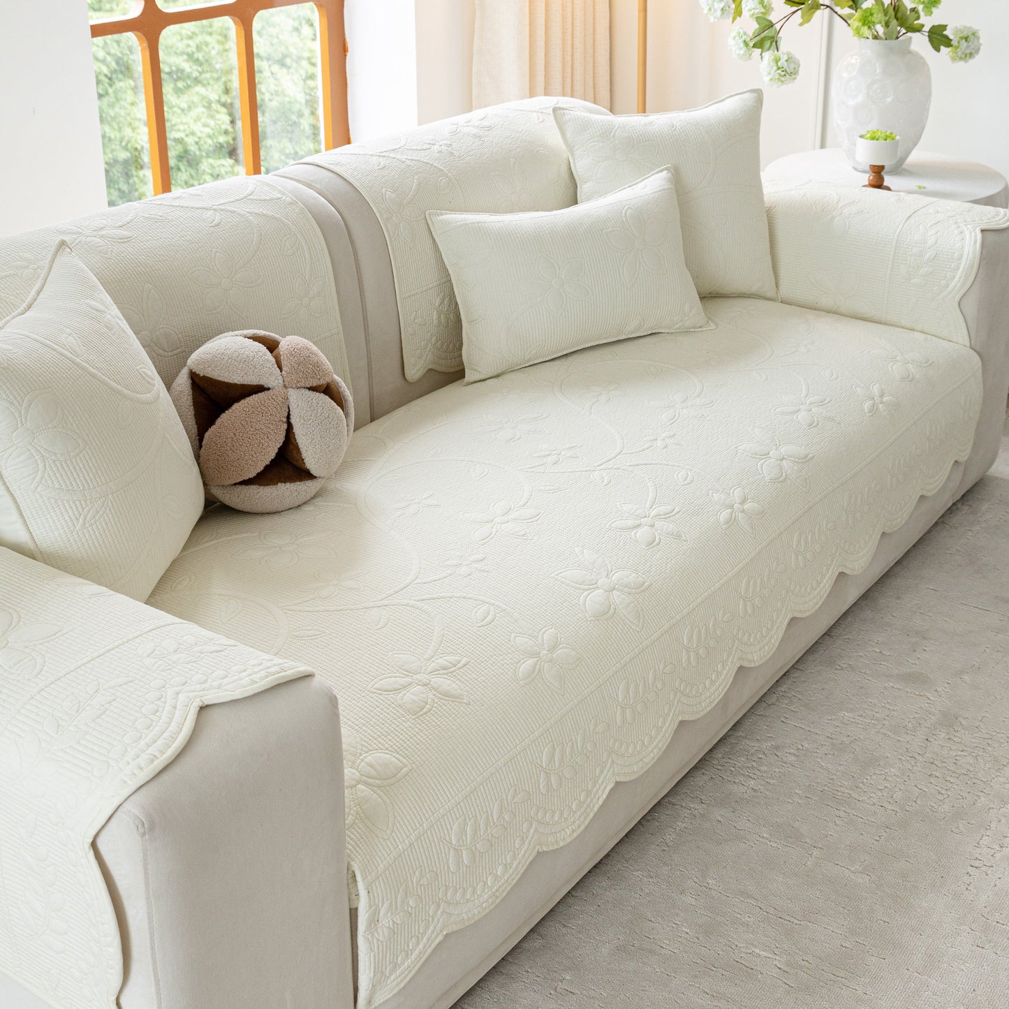 Floral Cotton Quilted Sofa Cover, Non-Slip Couch Protector with Scalloped Edges; elegant white cover on sofa with floral embroidery.