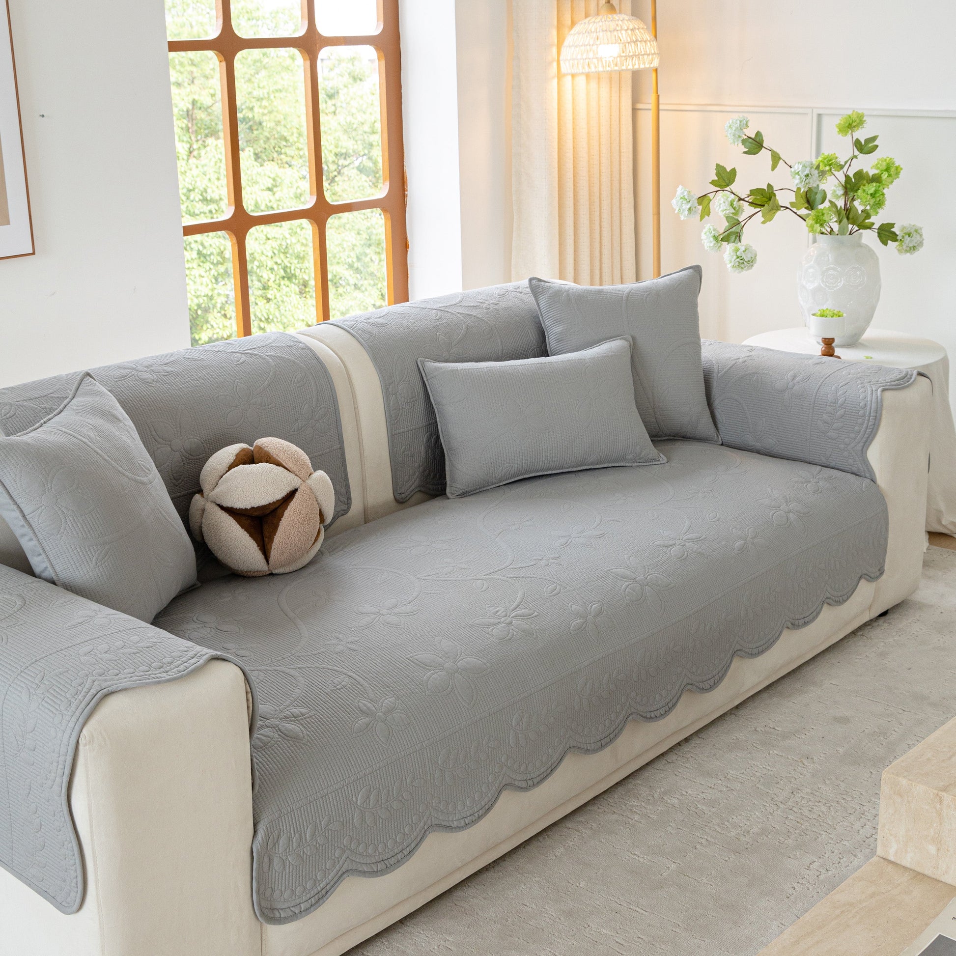 Floral Cotton Quilted Sofa Cover, Non-Slip Couch Protector with Scalloped Edges in a cozy living room setting.