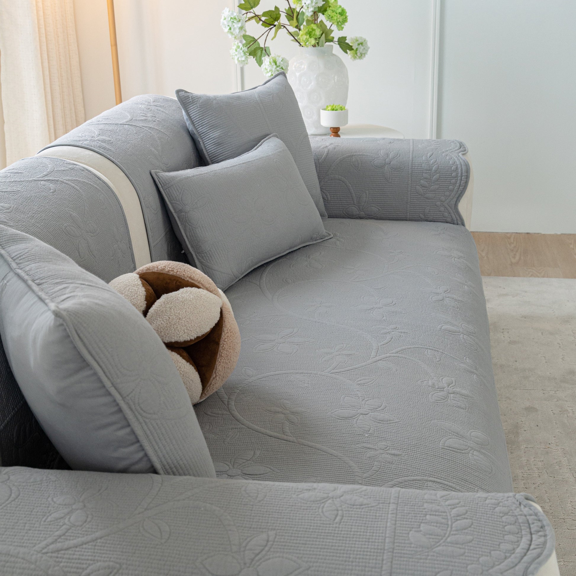 Floral Cotton Quilted Sofa Cover, Non-Slip Couch Protector with Scalloped Edges in a cozy living room setting.