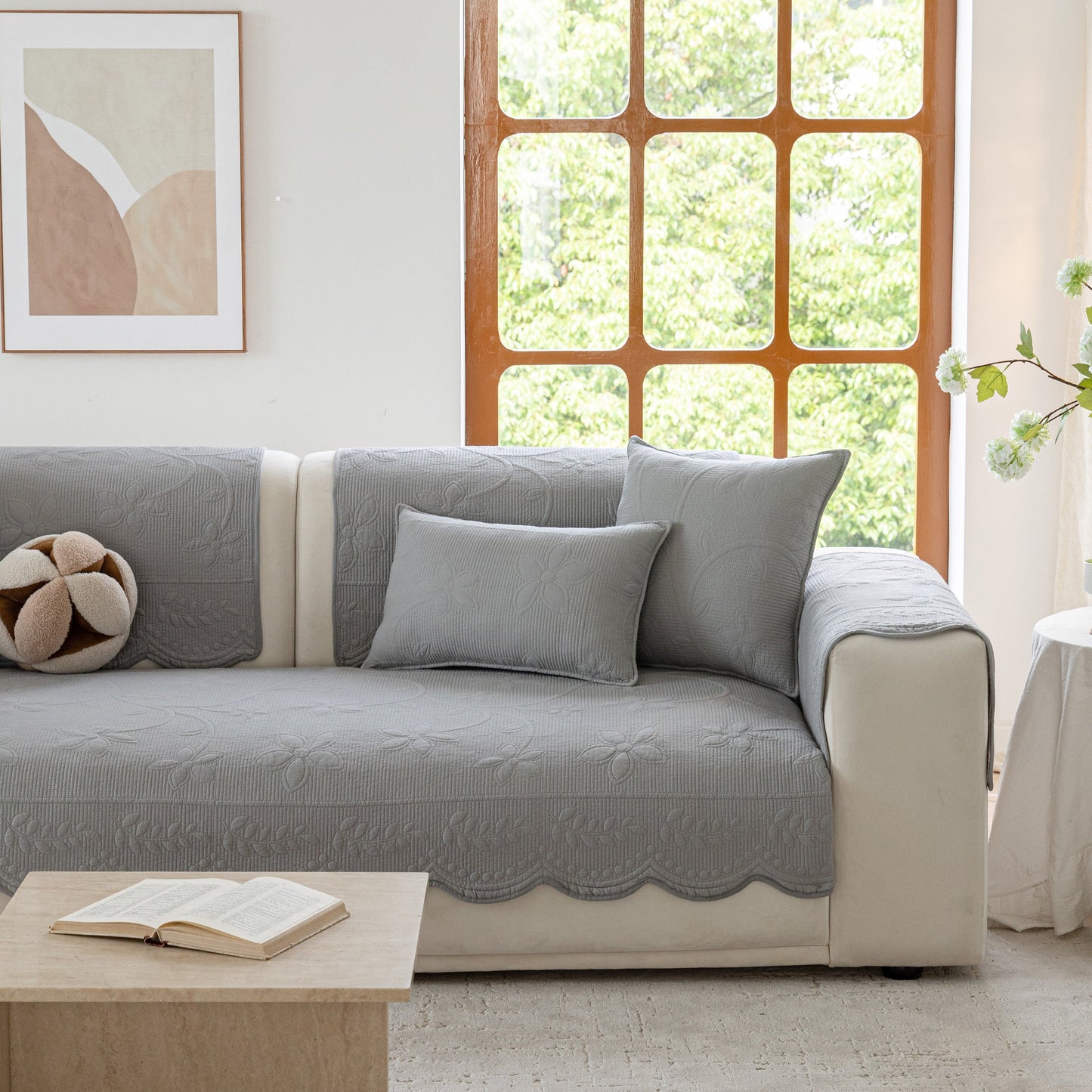 Floral Cotton Quilted Sofa Cover, Non-Slip Couch Protector with Scalloped Edges on a beige couch in a bright living room.