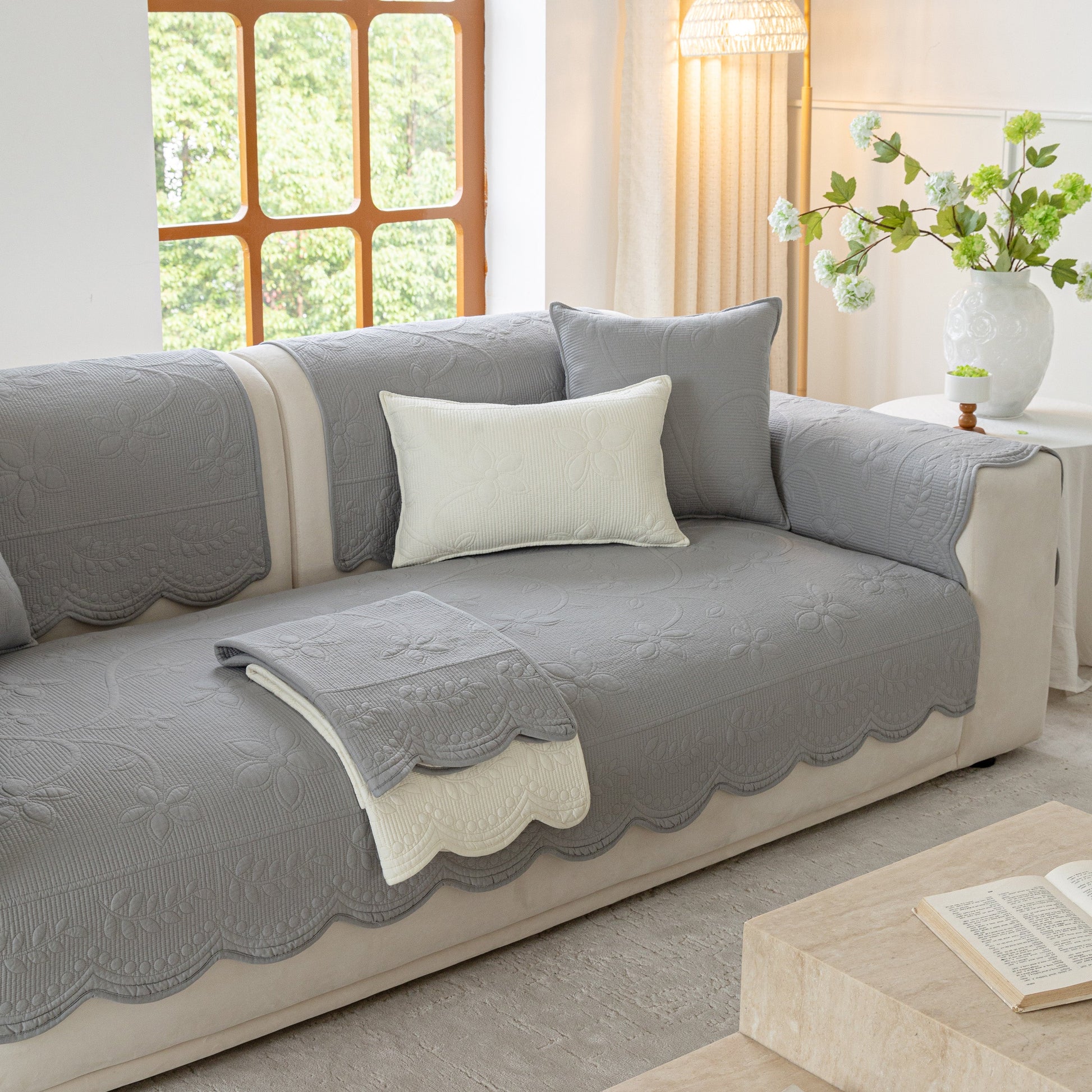 Floral Cotton Quilted Sofa Cover, Non-Slip Couch Protector with Scalloped Edges on a beige sofa in a cozy living room setting.