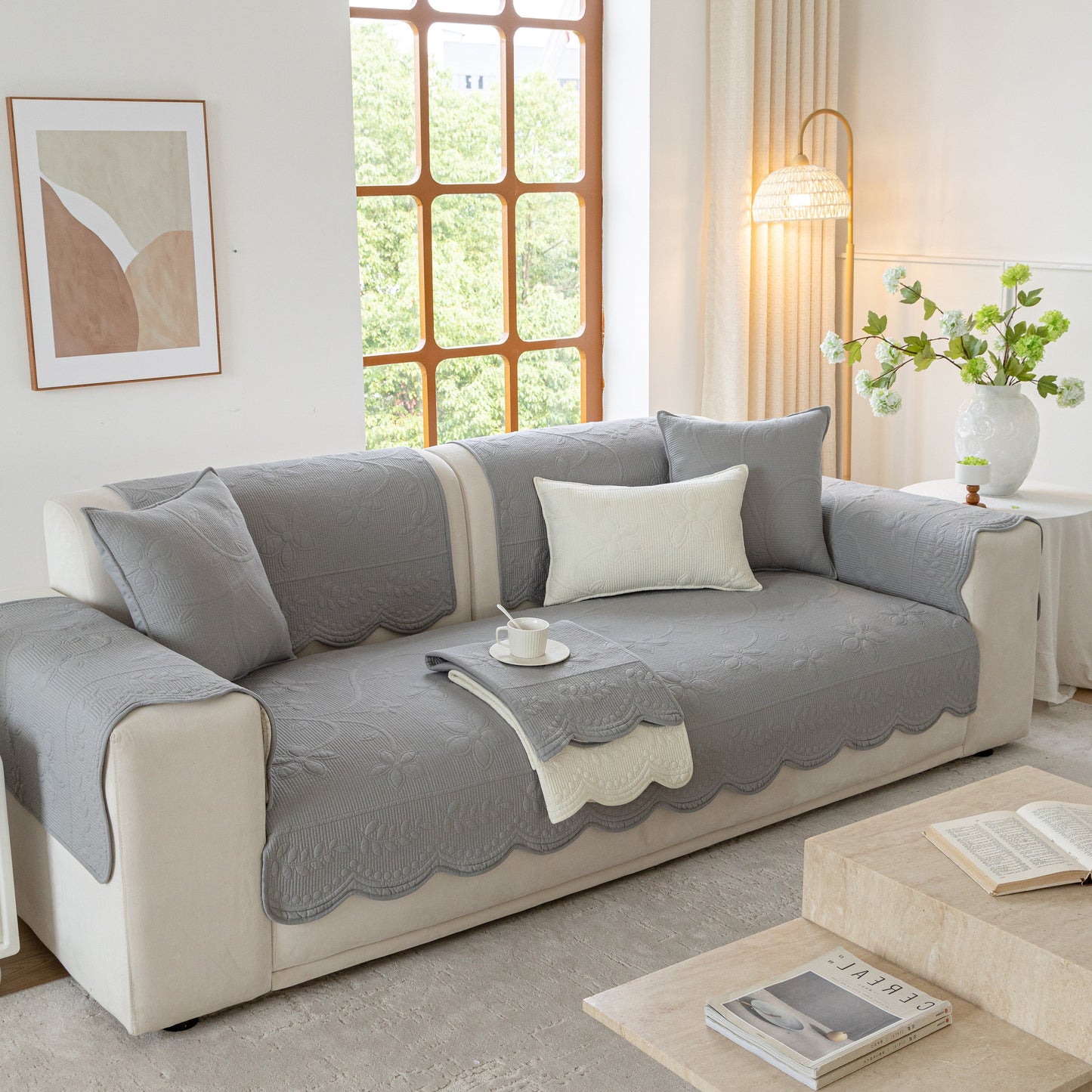 Cozy floral cotton quilted sofa cover, non-slip couch protector with scalloped edges, enhancing comfort and style in living room.