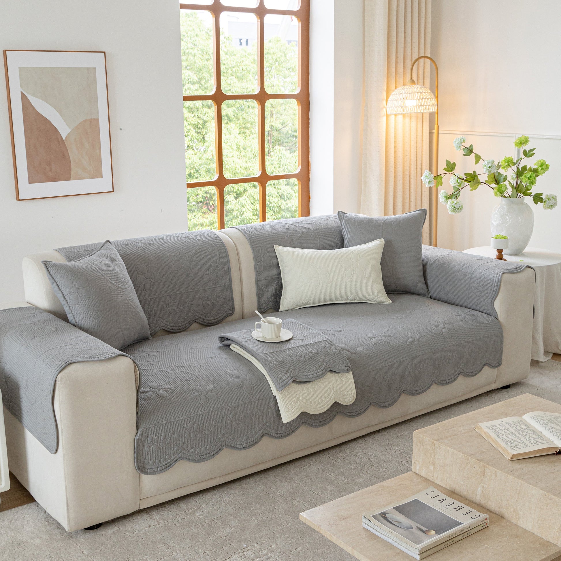 Cozy floral cotton quilted sofa cover, non-slip couch protector with scalloped edges, enhancing comfort and style in living room.