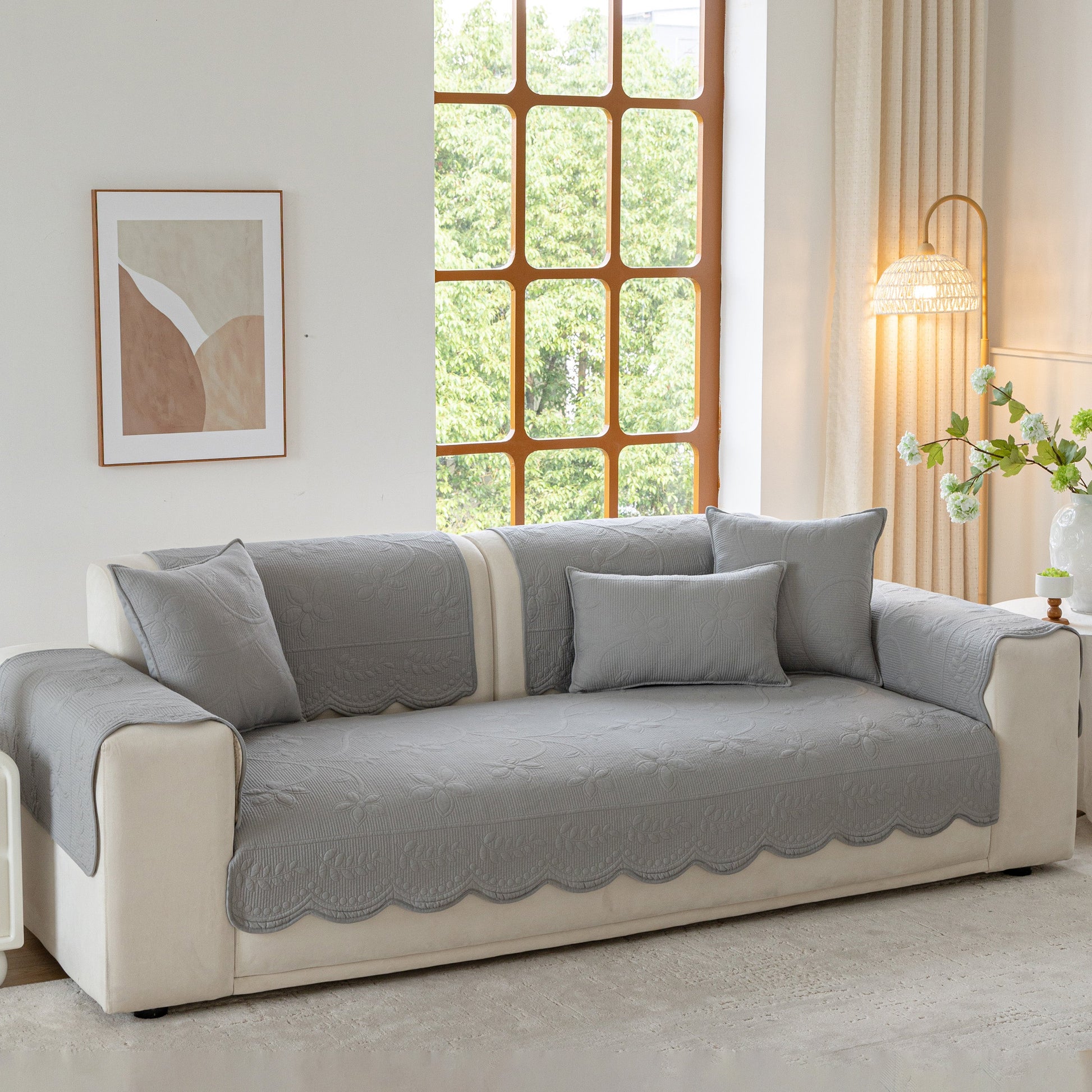 Floral Cotton Quilted Sofa Cover, Non-Slip Couch Protector with Scalloped Edges on a beige sofa in a cozy living room.