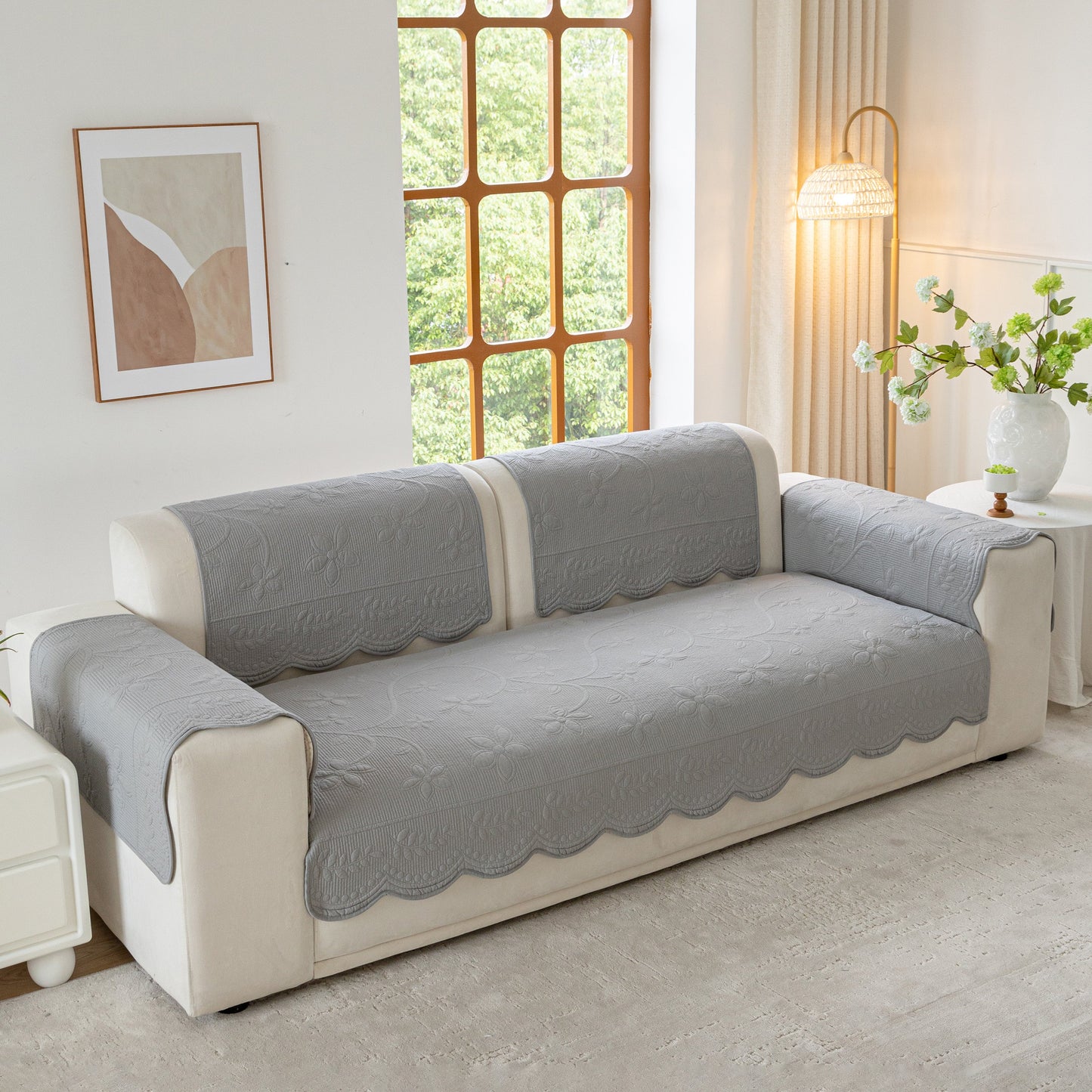 Floral Cotton Quilted Sofa Cover, Non-Slip Couch Protector with Scalloped Edges on a beige sofa in a bright living room.