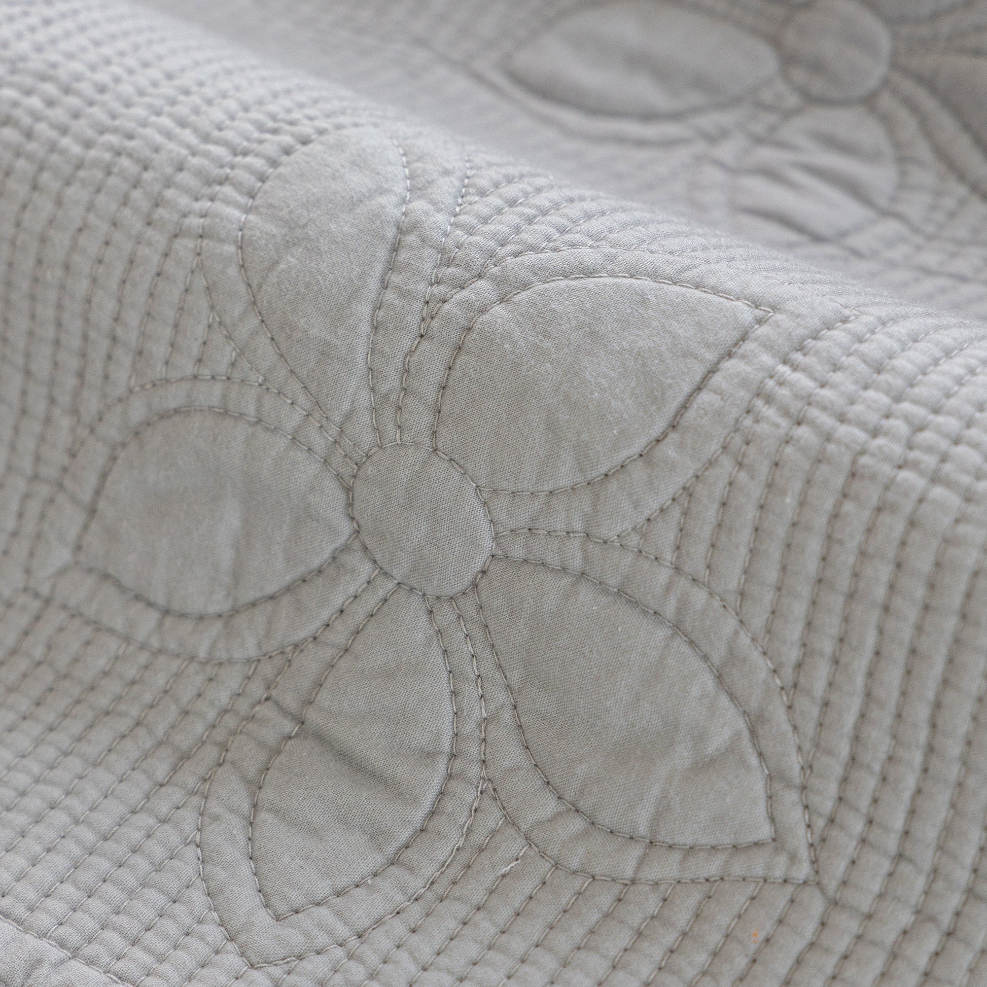 Close-up of Floral Cotton Quilted Sofa Cover, Non-Slip Couch Protector with Scalloped Edges showing floral embroidery detail.