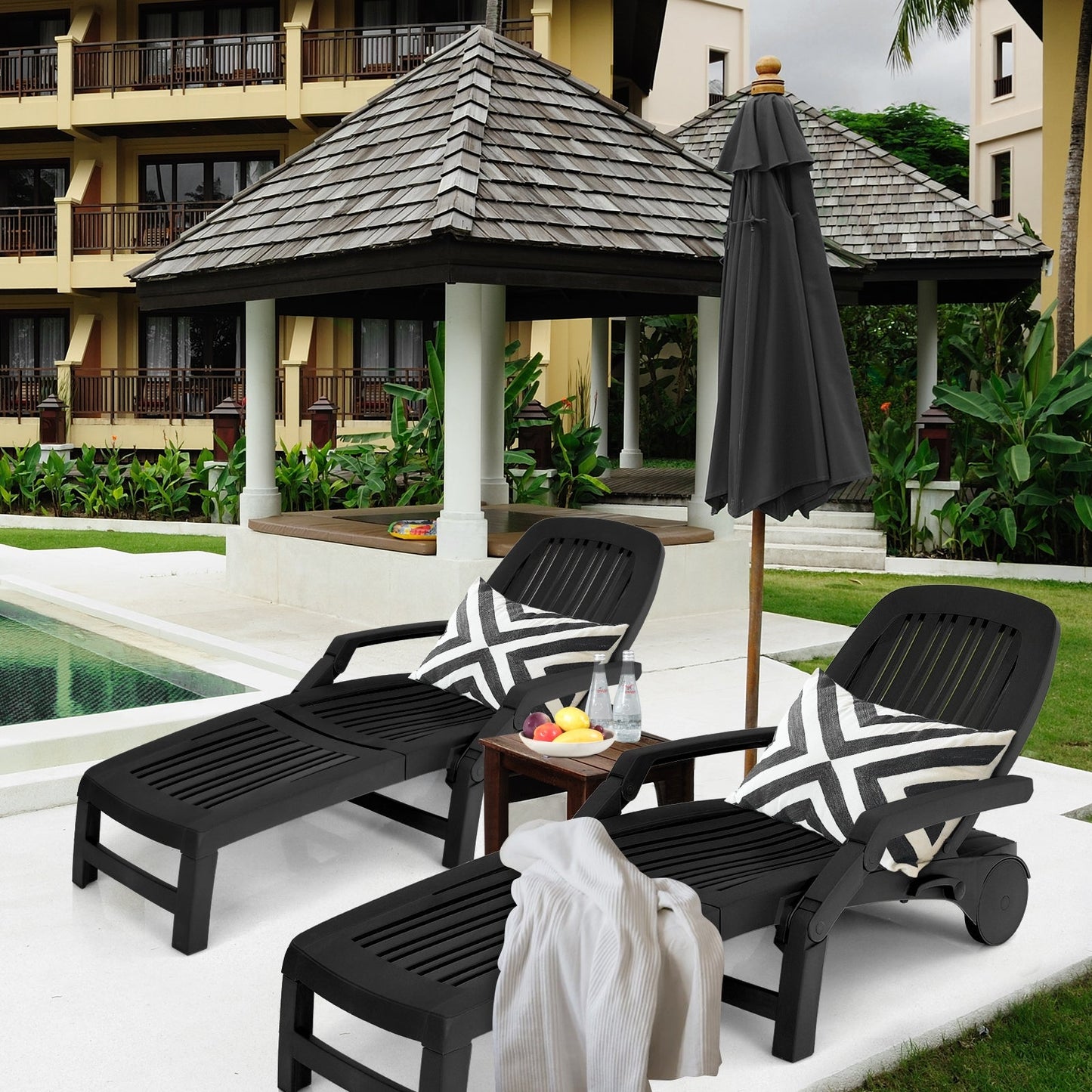 Adjustable Patio Sun Lounger with Weather Resistant Wheels-Black by a poolside with pillows and umbrella