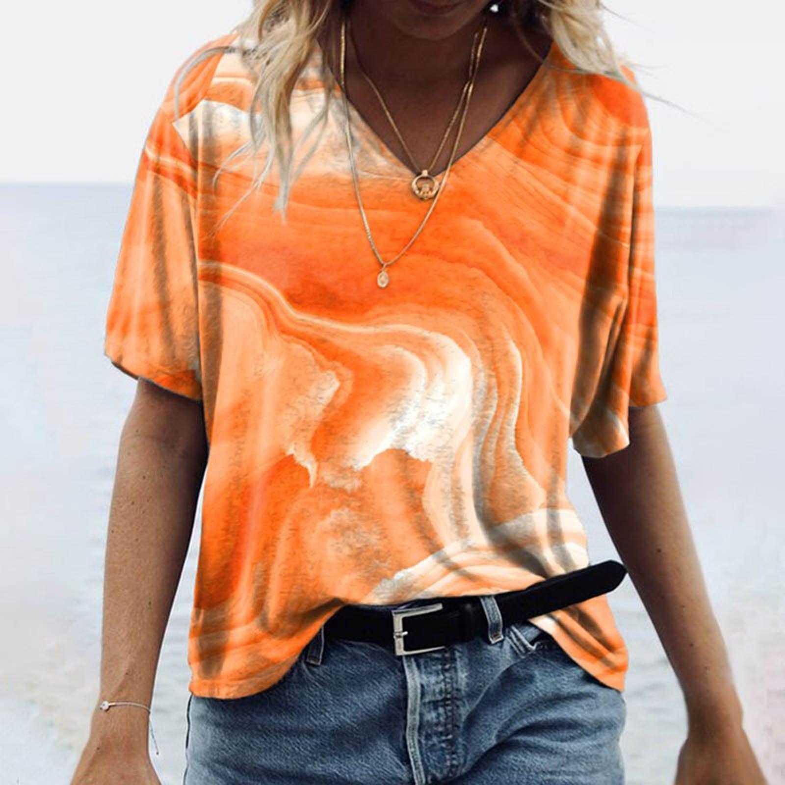 Woman wearing Women's Spring Glitzy V-Neck Short Sleeved Marble Print Top in vibrant orange marble design on the beach.