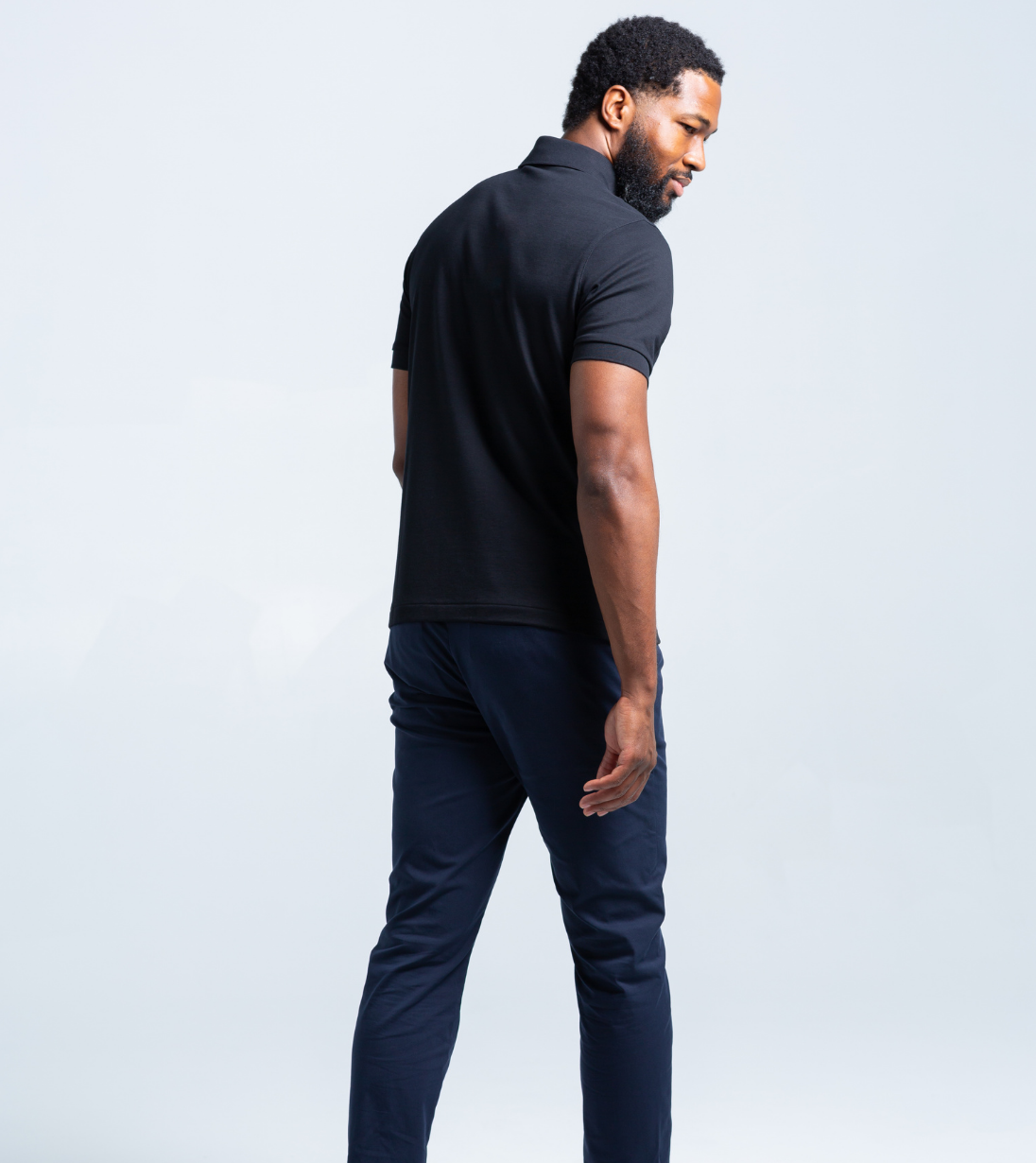 Man wearing a black Short Sleeve Perfect Polo showcasing tailored modern fit from the back view.