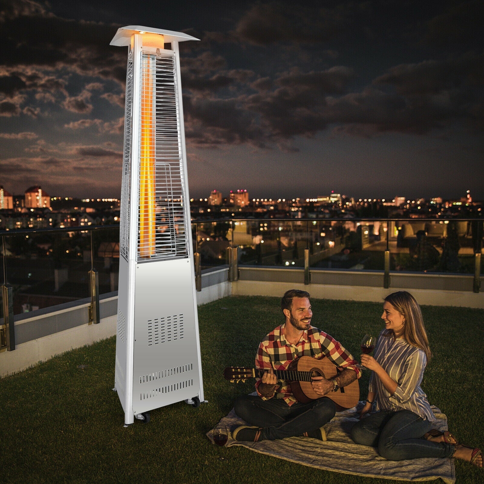 42 000 BTU Stainless Steel Pyramid Patio Heater With Wheels providing warmth on a rooftop evening with a couple enjoying music.