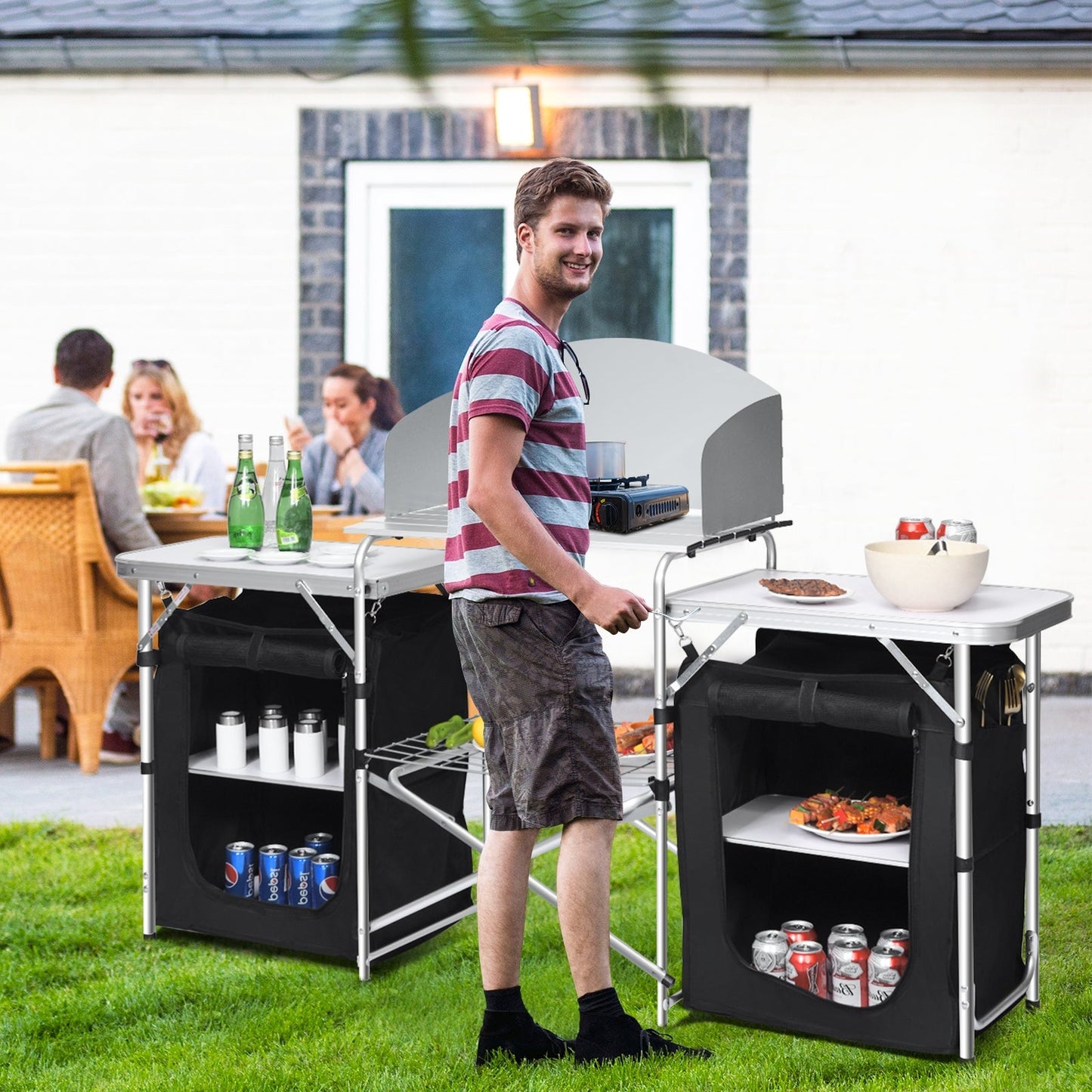 Man using Folding Camping Table with Storage Organizer-Black at outdoor barbecue with friends in garden setting.