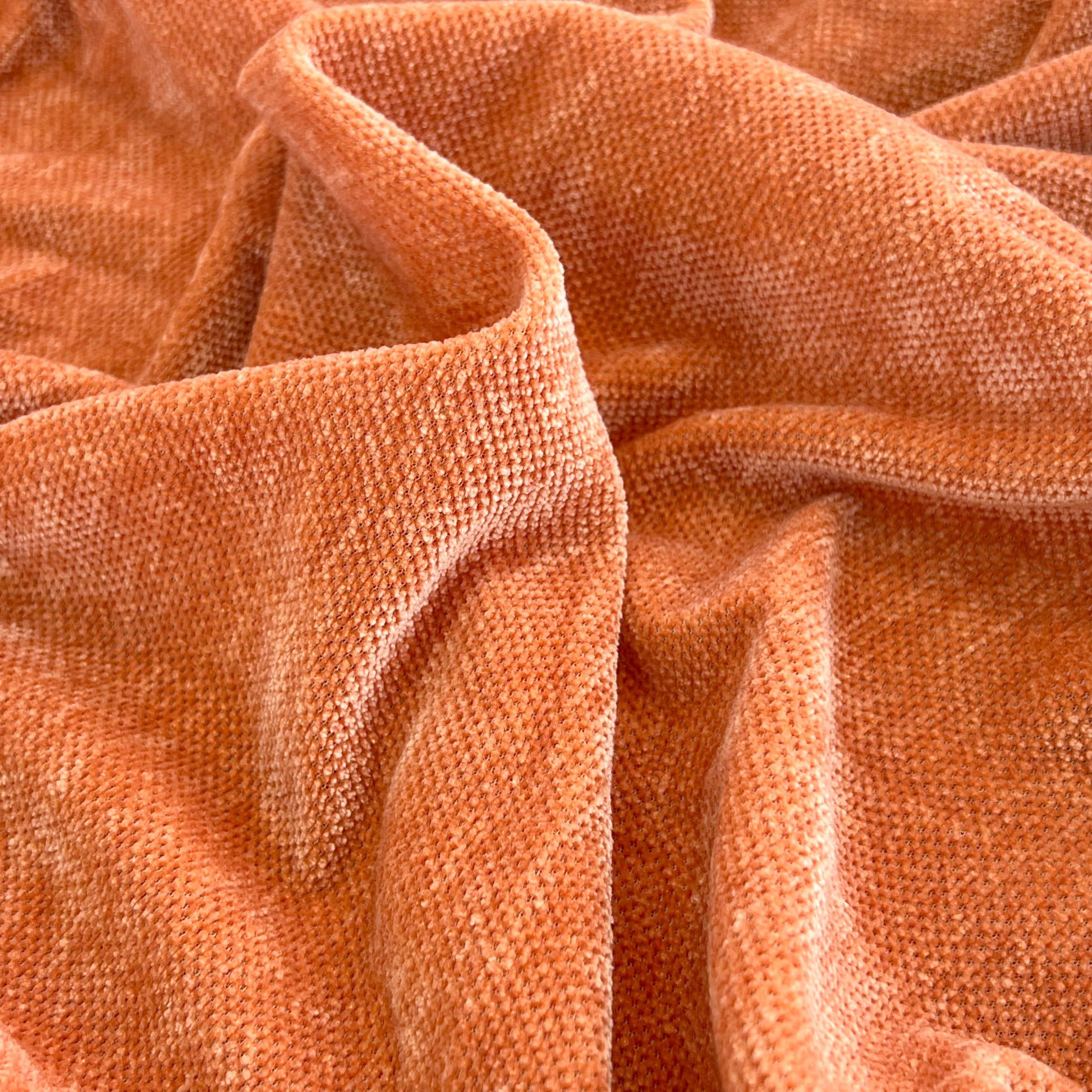 Close-up of Universal Elastic Skirt Sofa Slipcover fabric in a rich orange color, highlighting its texture and quality.