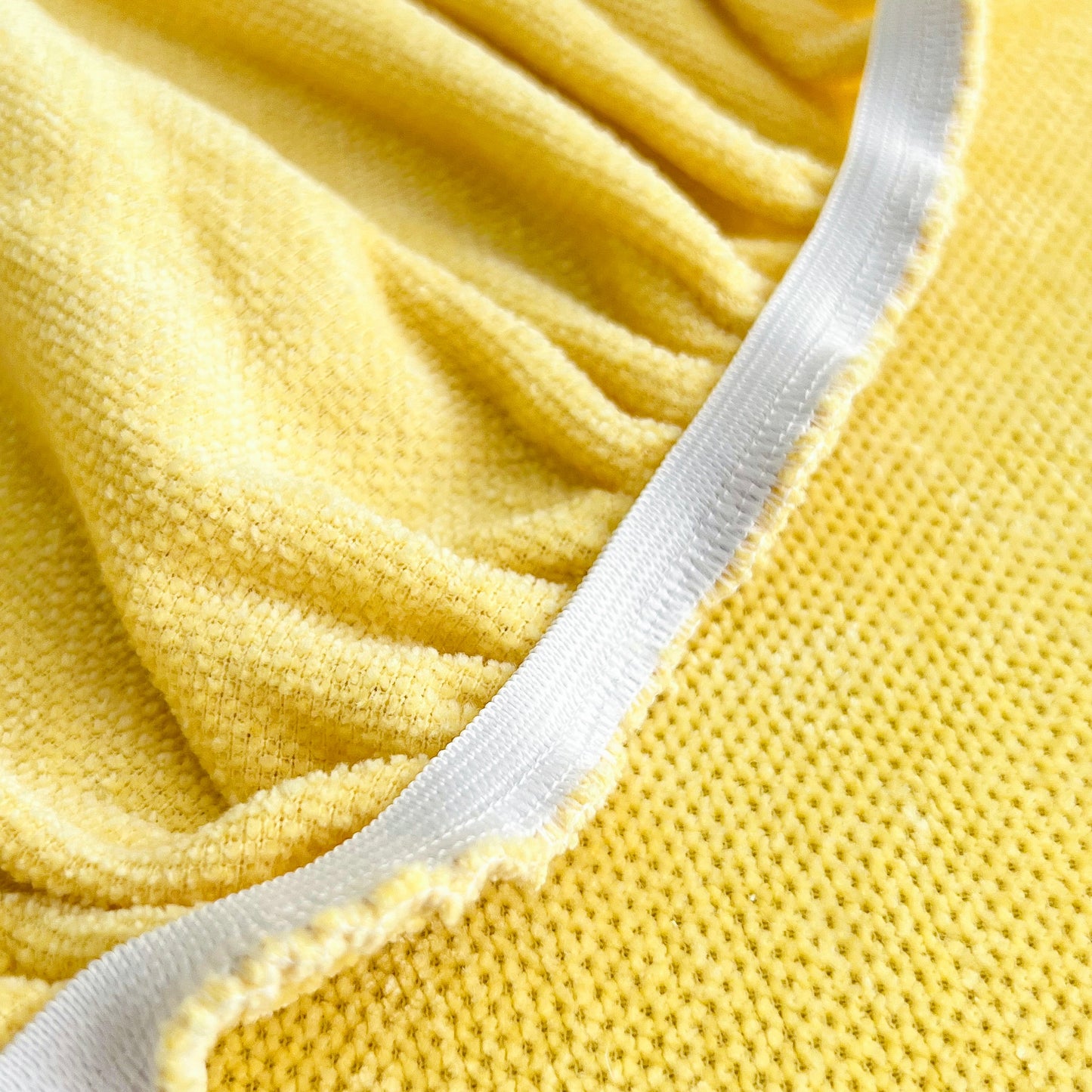 Close-up of Universal Elastic Skirt Sofa Slipcover fabric showing texture and elastic hem in yellow.