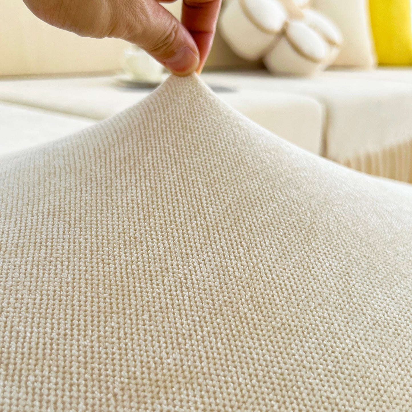 Close-up of Universal Elastic Skirt Sofa Slipcover showcasing its stretchability and texture on a sofa cushion in living room setting.