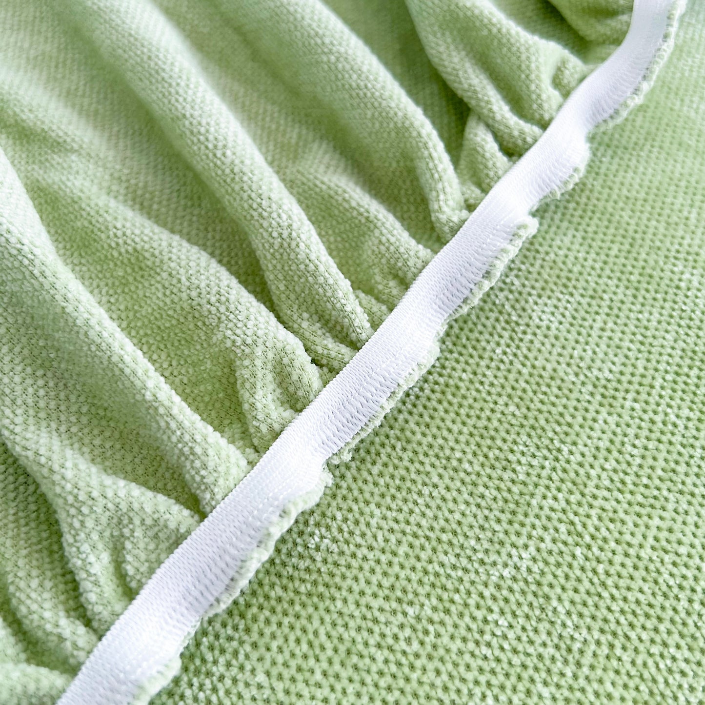 Close-up of Universal Elastic Skirt Sofa Slipcover fabric texture, showcasing green stretch sofa cushion cover for bedroom office living room.
