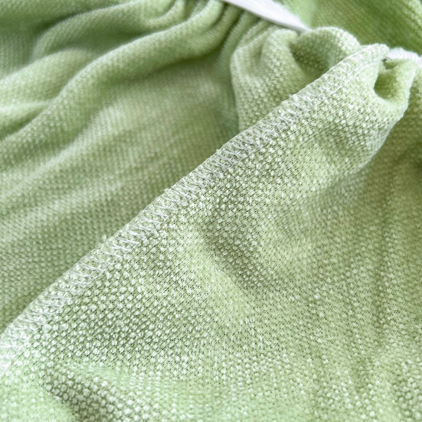 Close-up of Universal Elastic Skirt Sofa Slipcover in green chenille fabric, ideal for bedroom, office, living room furniture protection.