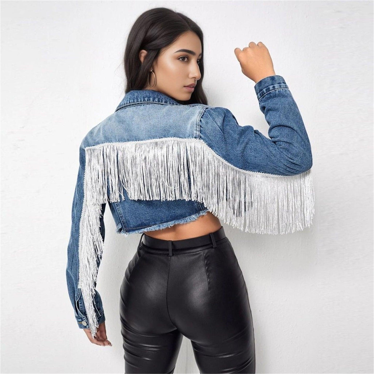 Model wearing Fringe Rider Short Denim Jacket with fringe detailing on sleeves, paired with black pants, showcasing back view.