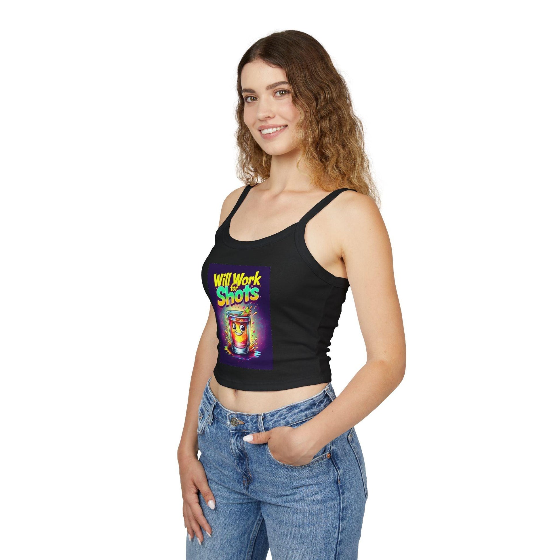 Smiling woman wearing black 'Will Work for Shots Womens Spaghetti Strap Tank Top' with colorful print, hands in jean pockets.