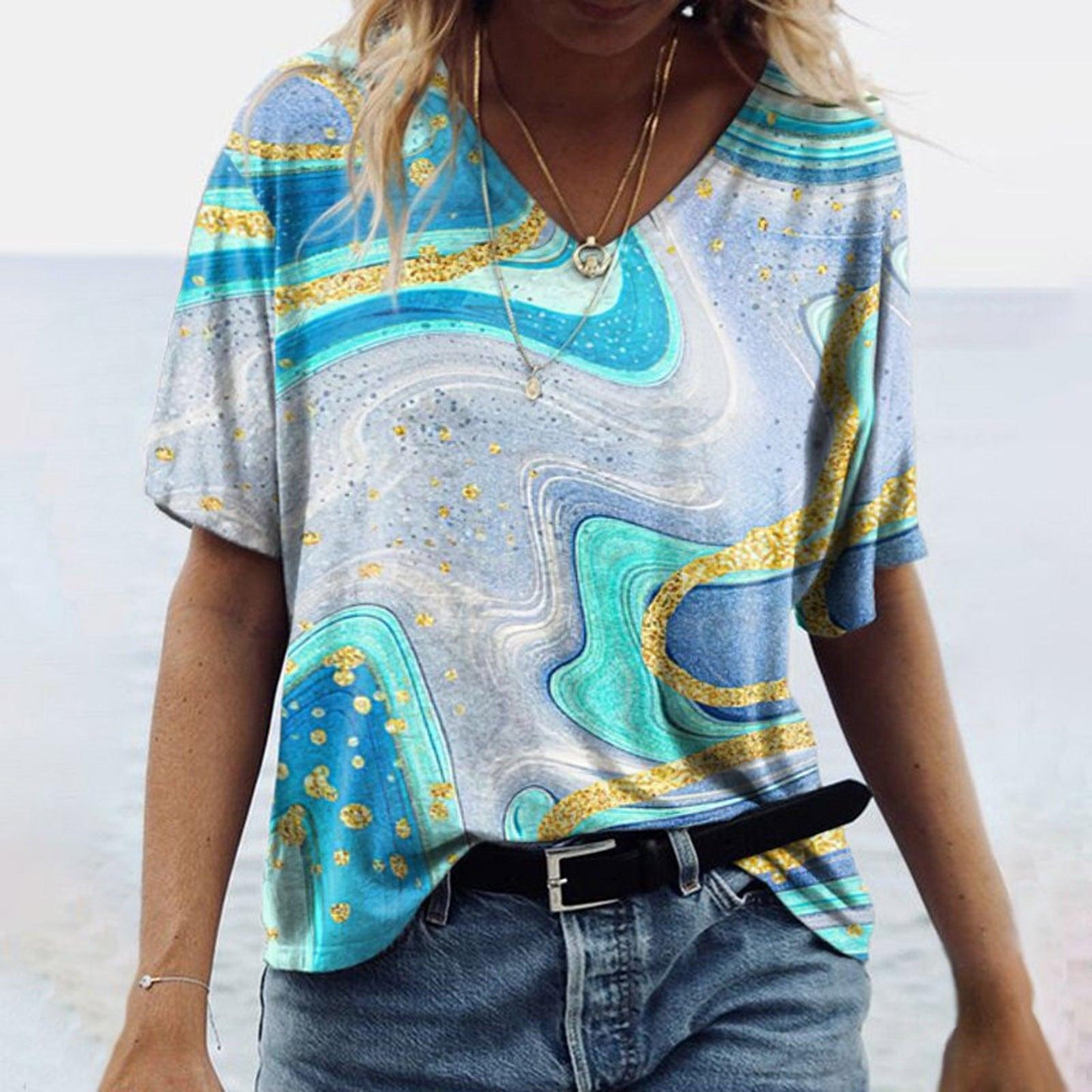 Woman wearing Women's Spring Glitzy V-Neck Short Sleeved Marble Print Top in vibrant blue and gold marble pattern.