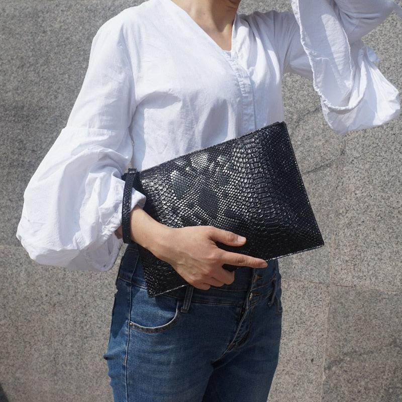Python Luxe Clutch - Stylish Simulated Leather Clutch for Sophisticated Women held by a woman in casual wear.