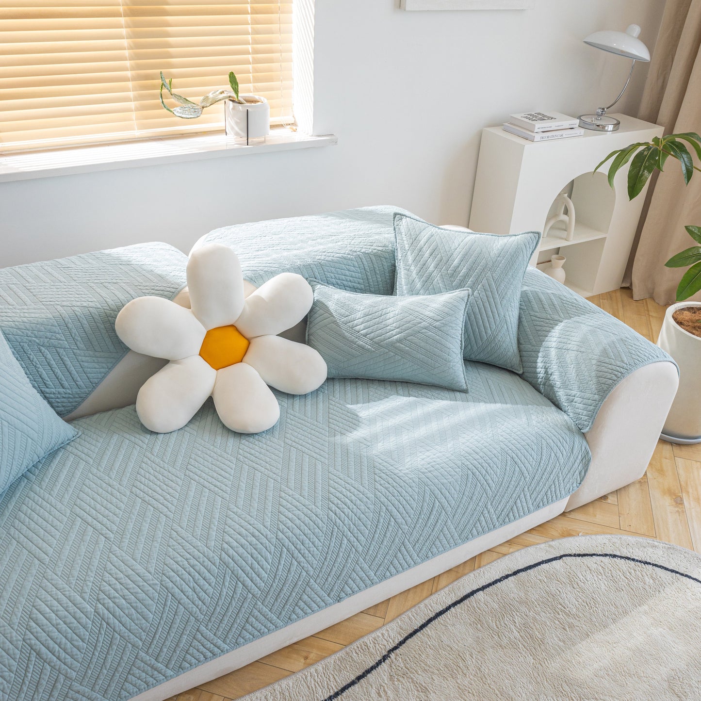 Quilted Geometric Cotton Sofa Cover, Non-Slip & Thick Padded Furniture Covers in light blue on sofa with cushions and flower pillow