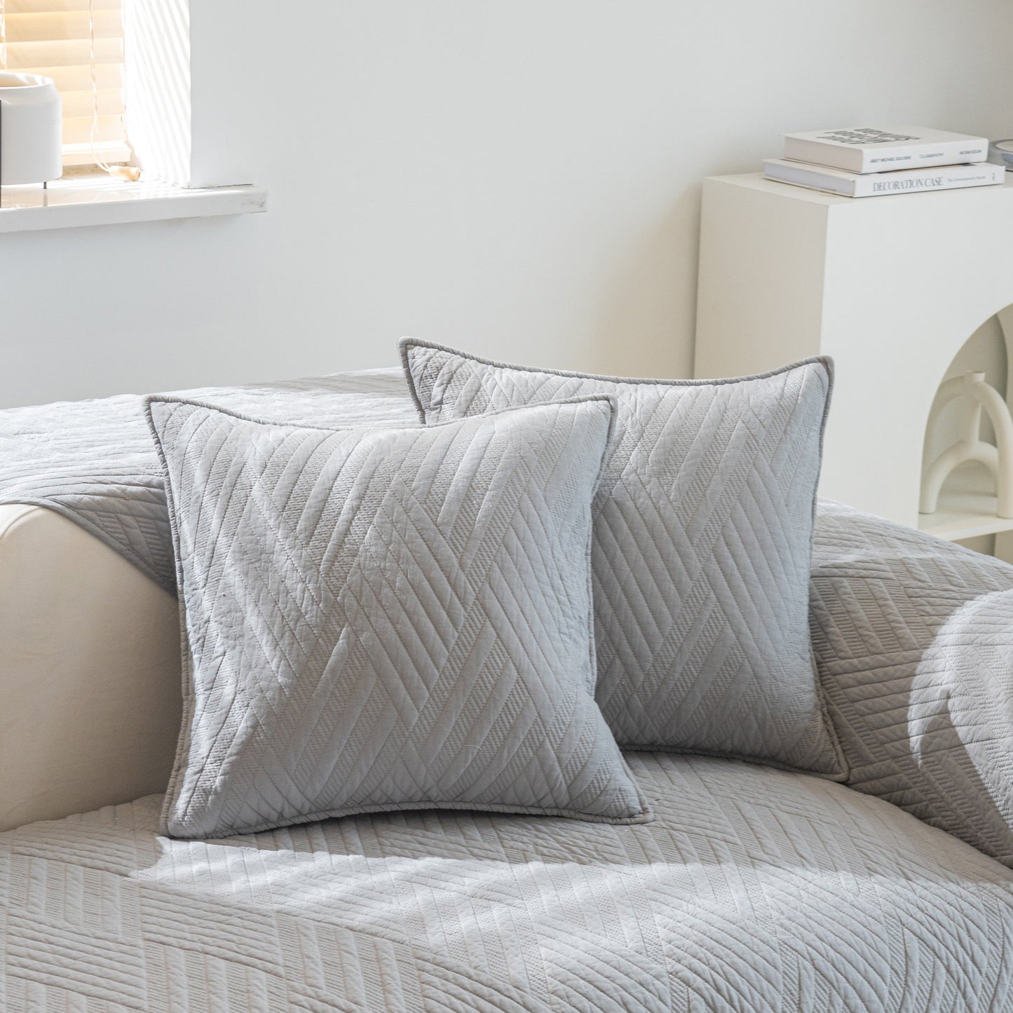 Quilted Geometric Cotton Sofa Cover, Non-Slip & Thick Padded Furniture Covers in light grey on a cream sofa with matching pillows.
