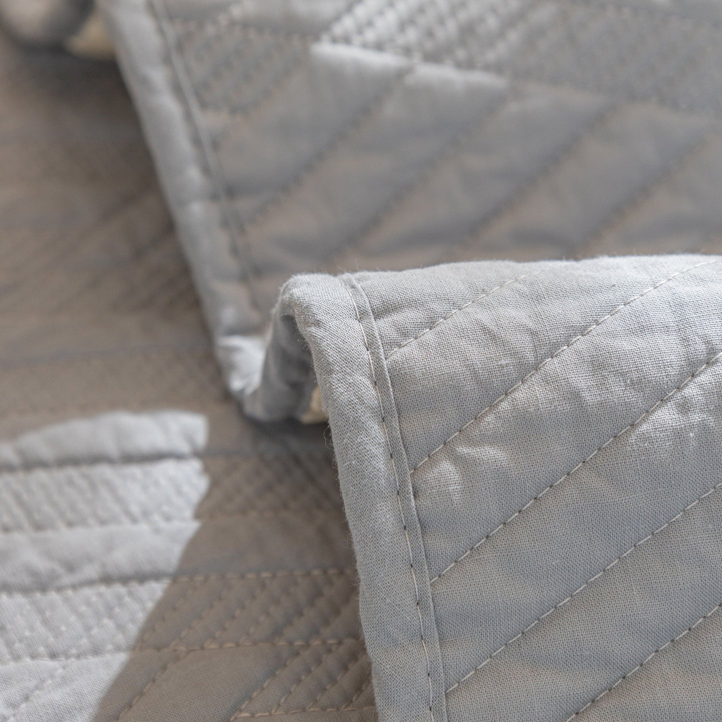 Close-up of Quilted Geometric Cotton Sofa Cover with non-slip backing, featuring thick padded design and textured diagonal stitching.