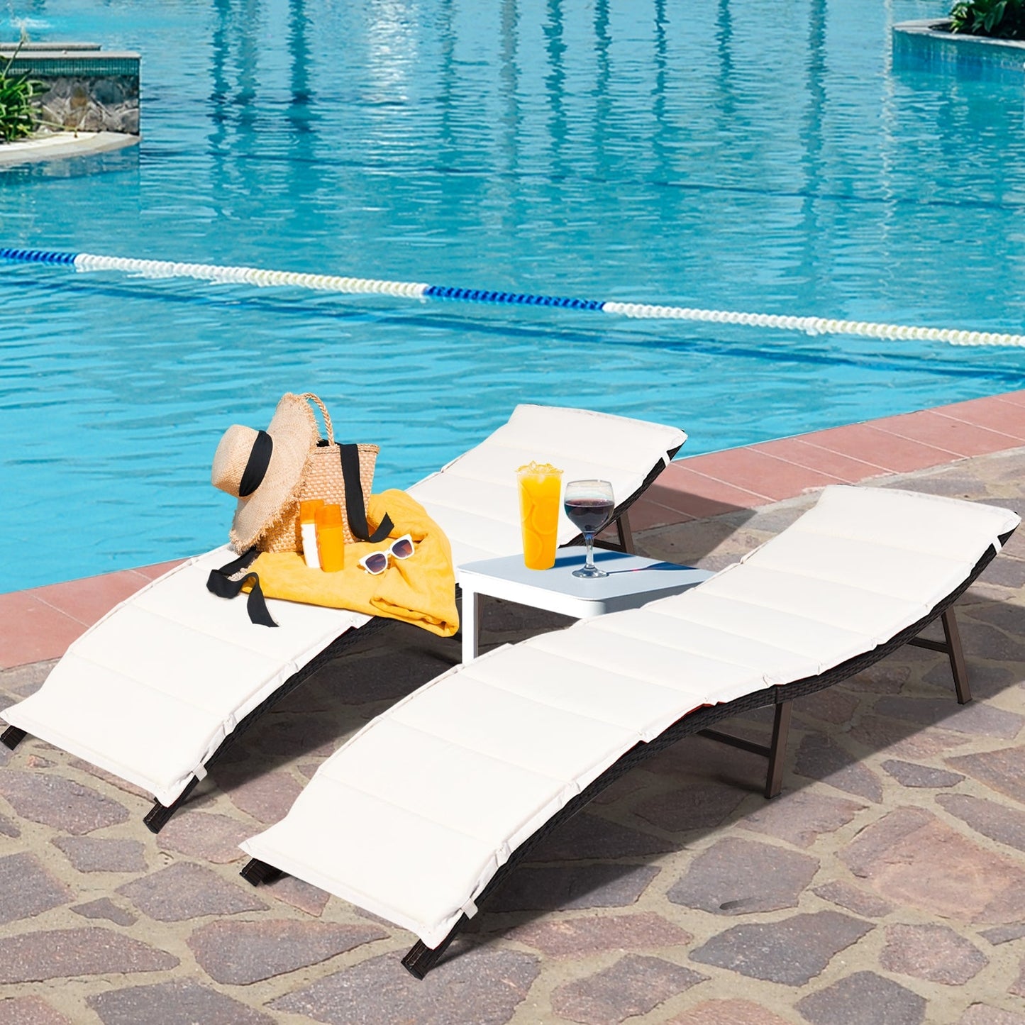 2Pcs Folding Patio Lounger Chair by the pool with drinks and sun hat, crafted with steel and wicker for stability and easy storage.