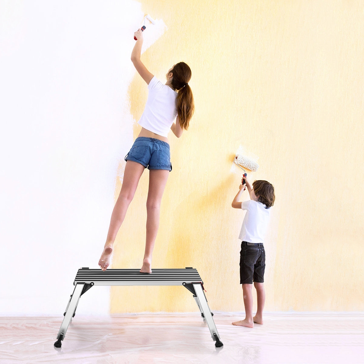 Woman using 330 lbs Aluminum Folding Non-slip Drywall Step Stool Ladder for painting walls, assisted by child with roller.