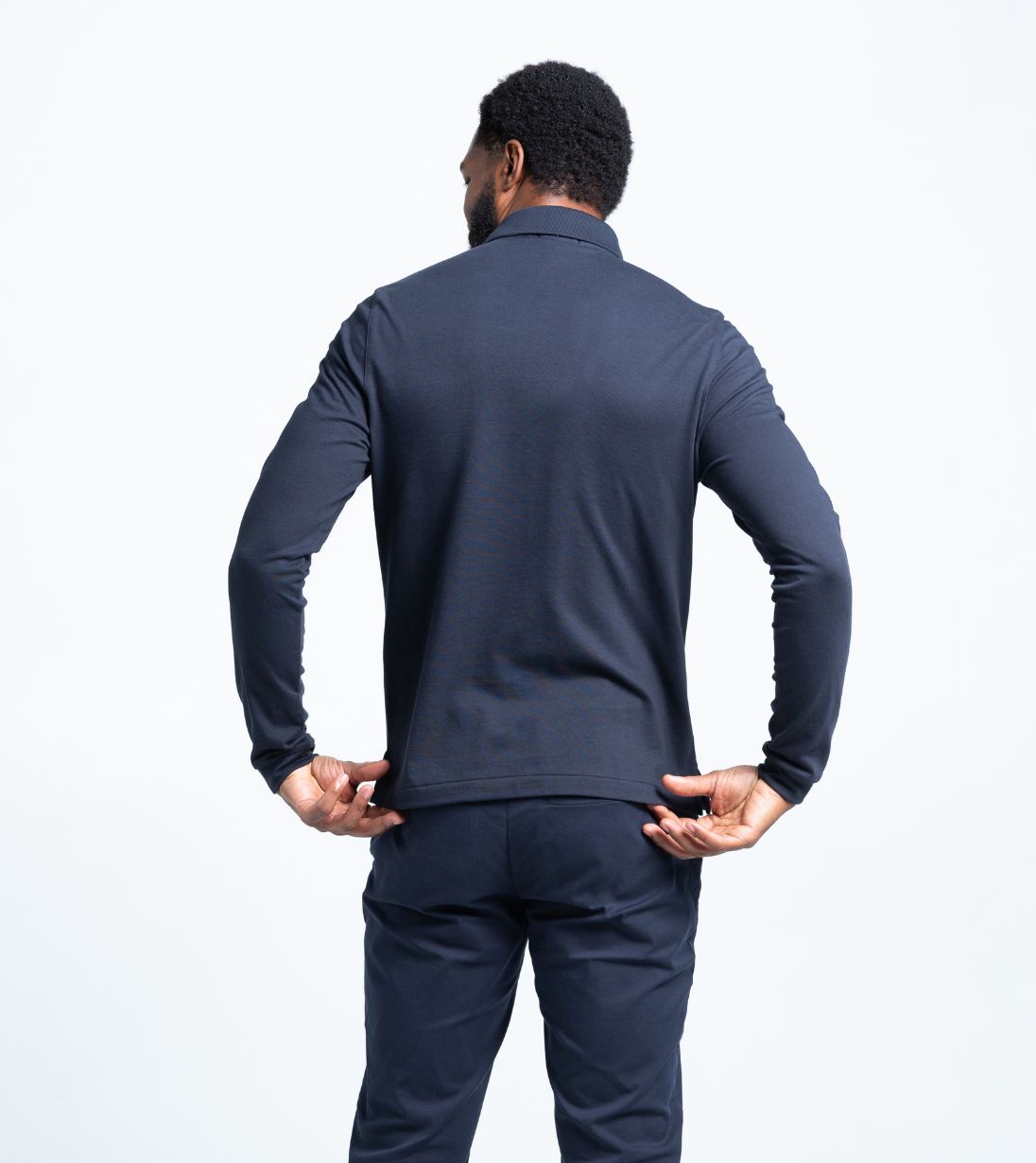 Back view of a man wearing a navy Baobab Long Sleeve Perfect Polo with StaySharp™ Collar and tailored fit.