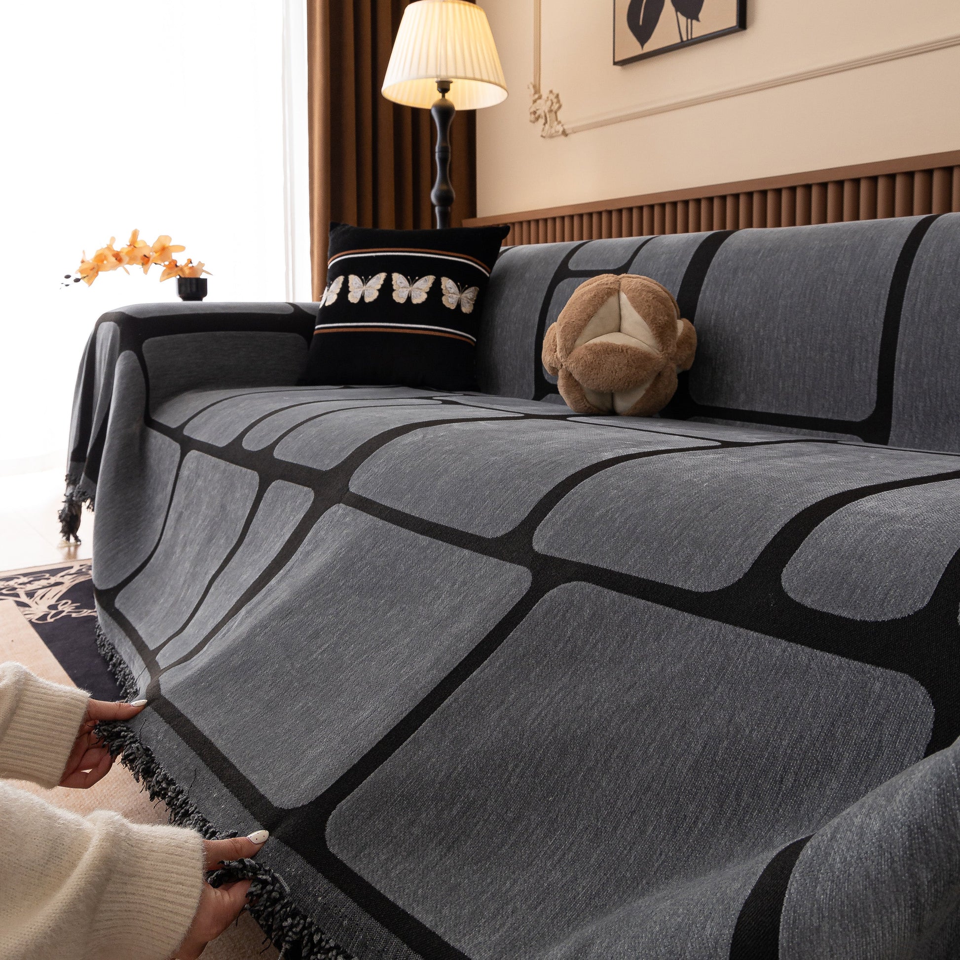 Modern Geometric Sofa Cover Decorative Couch Throw Blanket Furniture Protector on a gray couch with geometric pattern and tassels.