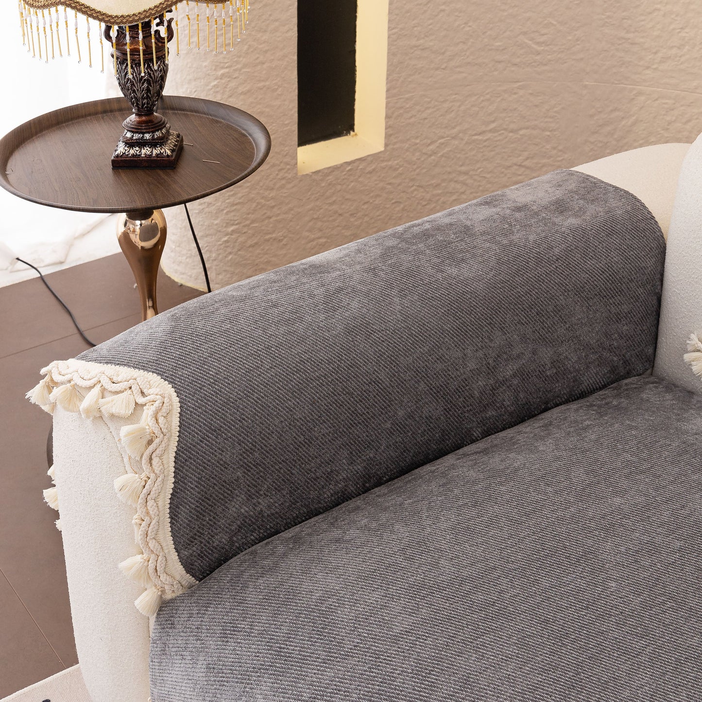 Chenille Sofa Cover Towel – Non-Slip, Washable Pets Couch Protector with Tassels on a gray sofa with braided trim and tassels.