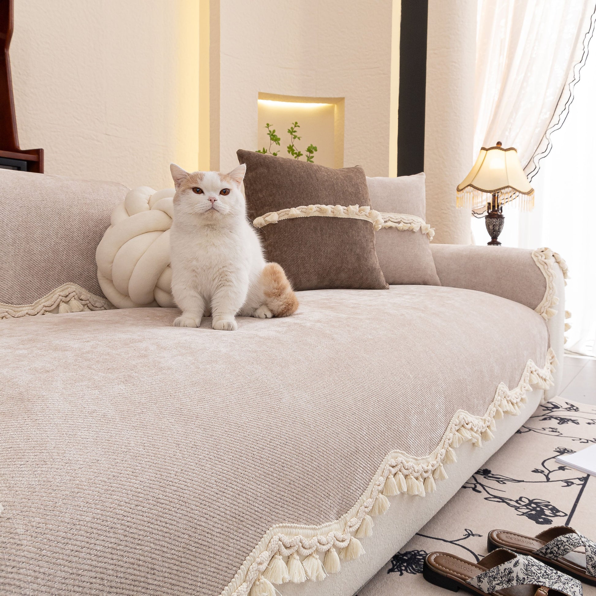 Chenille Sofa Cover Towel – Non-Slip, Washable Pets Couch Protector with Tassels on a sofa with a cat lounging on it.