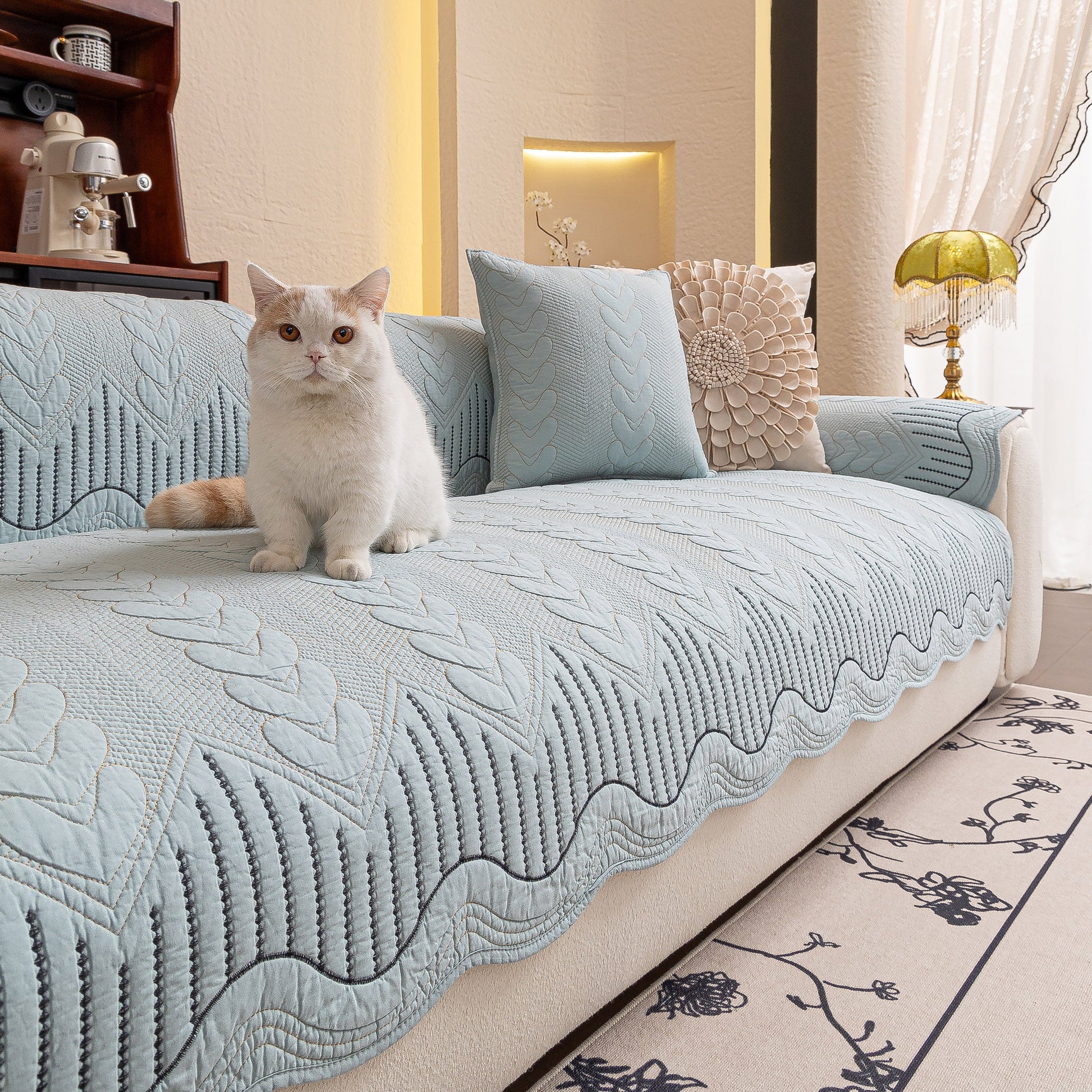 Cat sitting on 3D Quilted Thick Cotton Sofa Cover Non-Slip Couch Throw for Fabric & Leather Sofas, blue cover on a white couch.
