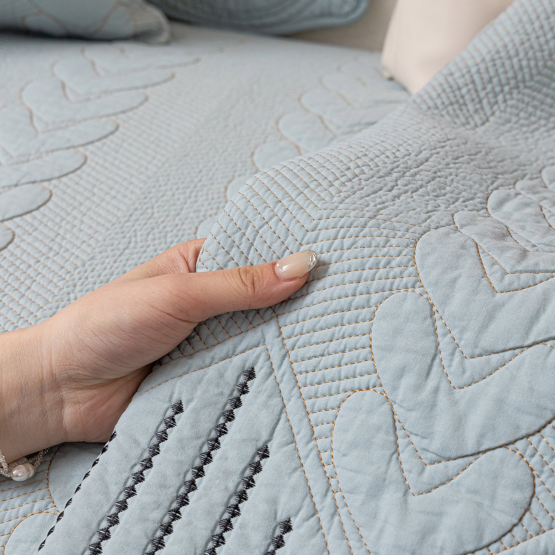 Close-up of hand touching 3D Quilted Thick Cotton Sofa Cover Non-Slip Couch Throw for Fabric & Leather Sofas with detailed quilting.