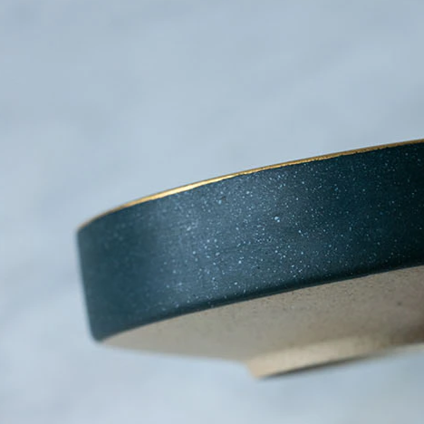 Close-up of Galileo Tableware plate with matte green glaze and gold rim, handcrafted porcelain, dishwasher and freezer safe.
