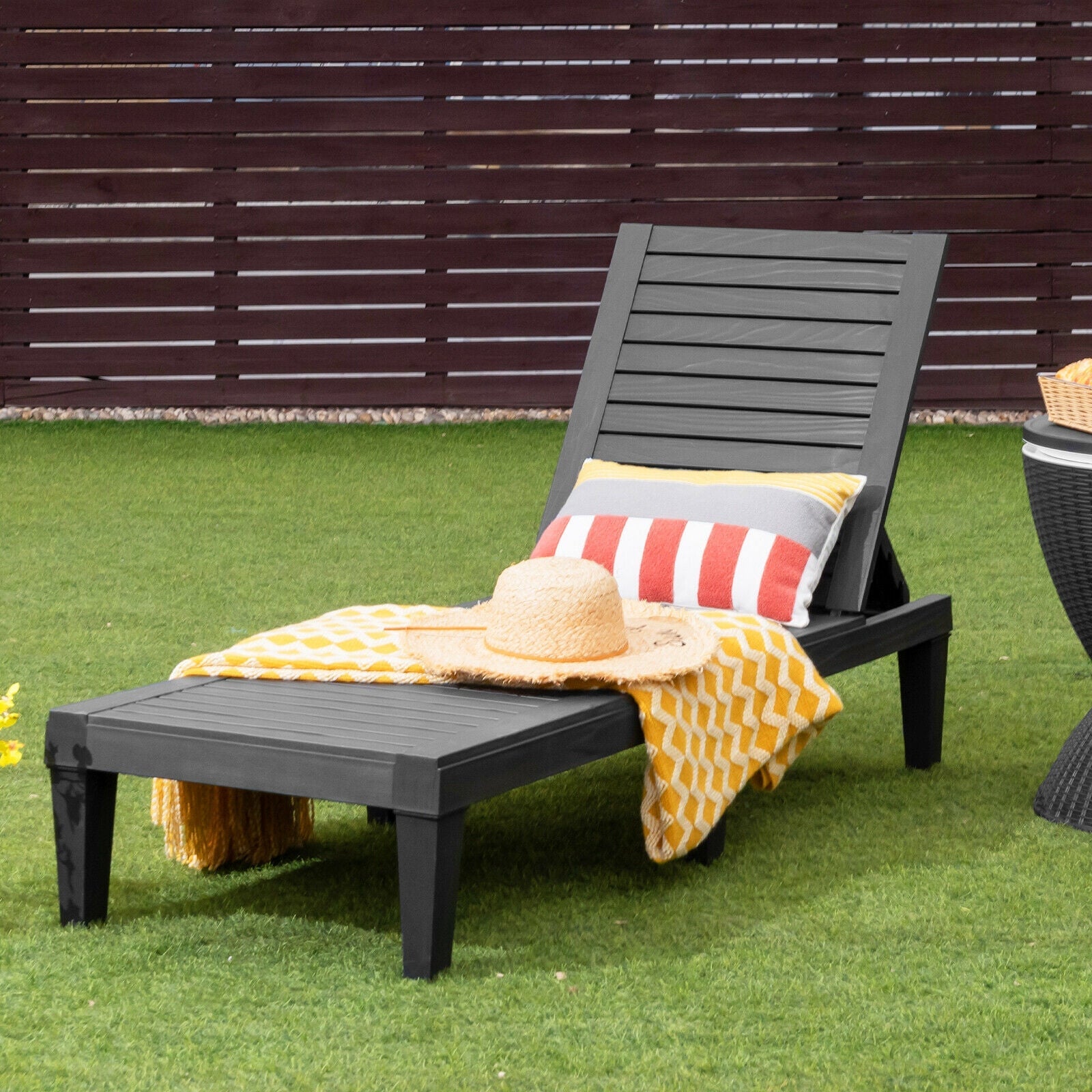 Outdoor Recliner Chair with 5-Position Adjustable Backrest-Black on patio lawn with striped pillows and hat