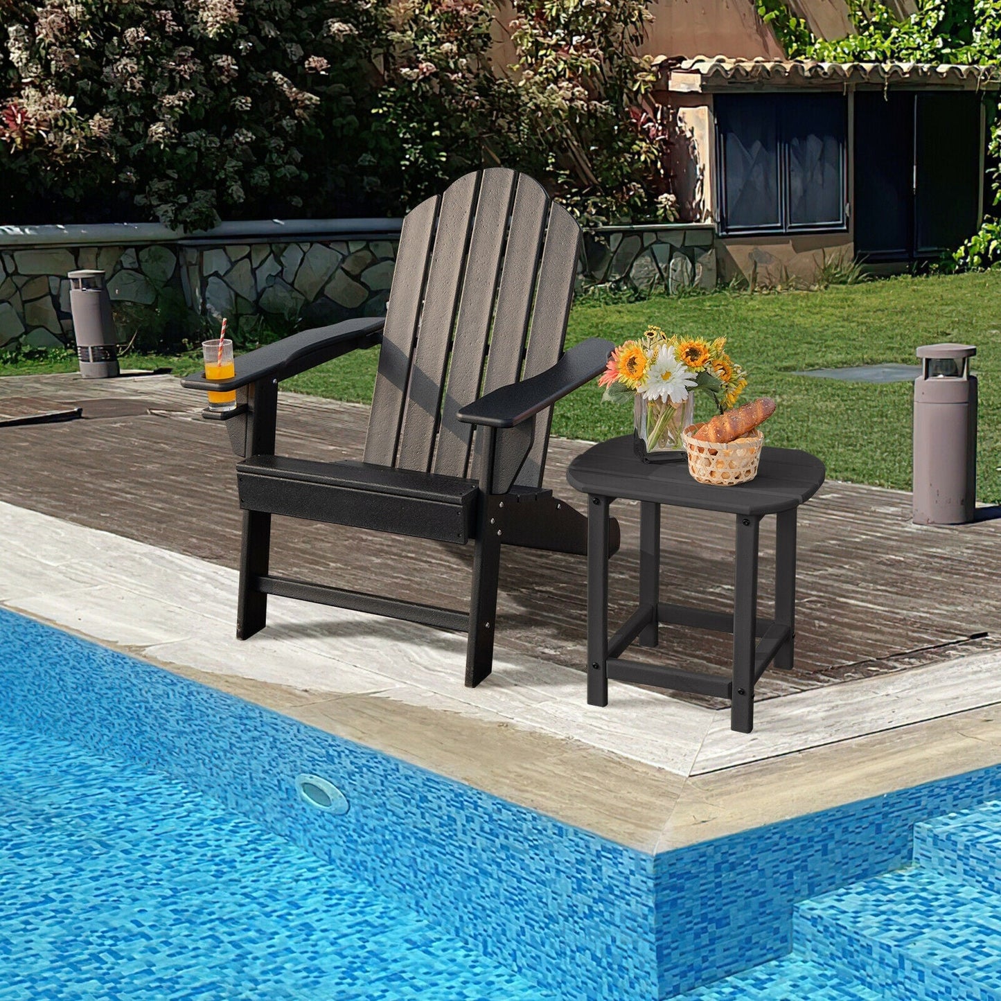 Outdoor Adirondack Chair with Built-in Cup Holder for Backyard Porch-Black by the poolside with a small table and flowers.