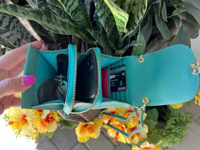 Open Country Club Clutches showing compartments and zipped pocket, crafted from textured leather, set against a floral backdrop.
