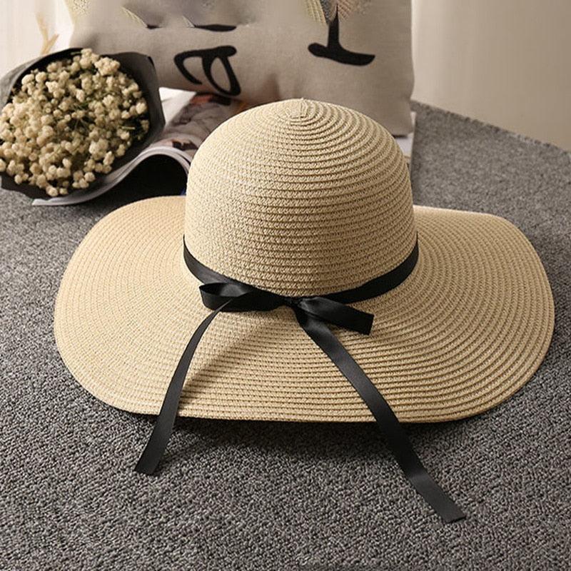 La Dolce Vita Straw Hat - Stylish Italian Summer Sun Hat with Ribbon Tie on a gray surface with black ribbon detail.