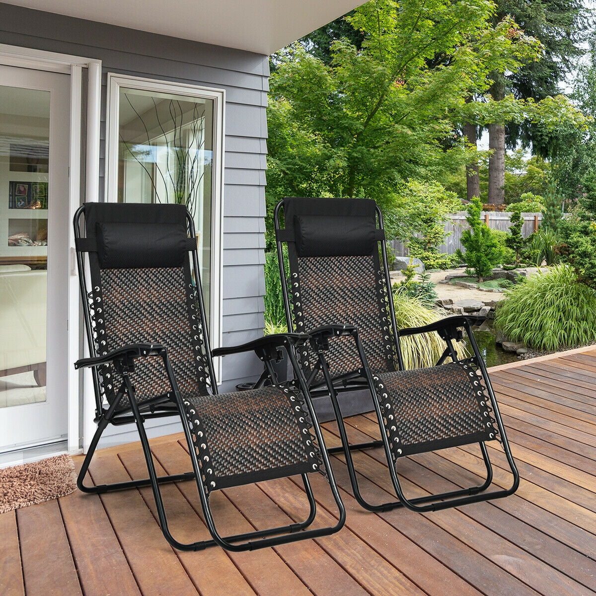 2 Pieces Folding Patio Rattan Zero Gravity Lounge Chair-Brown set on a wooden deck with garden background.