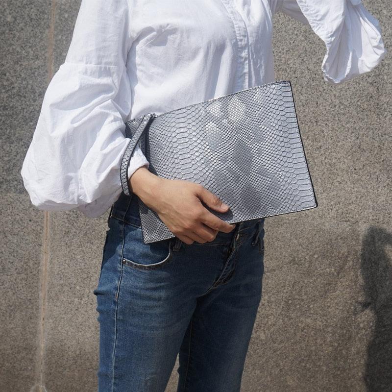 Python Luxe Clutch - Stylish Simulated Leather Clutch for Sophisticated Women held by a model wearing white shirt and jeans.