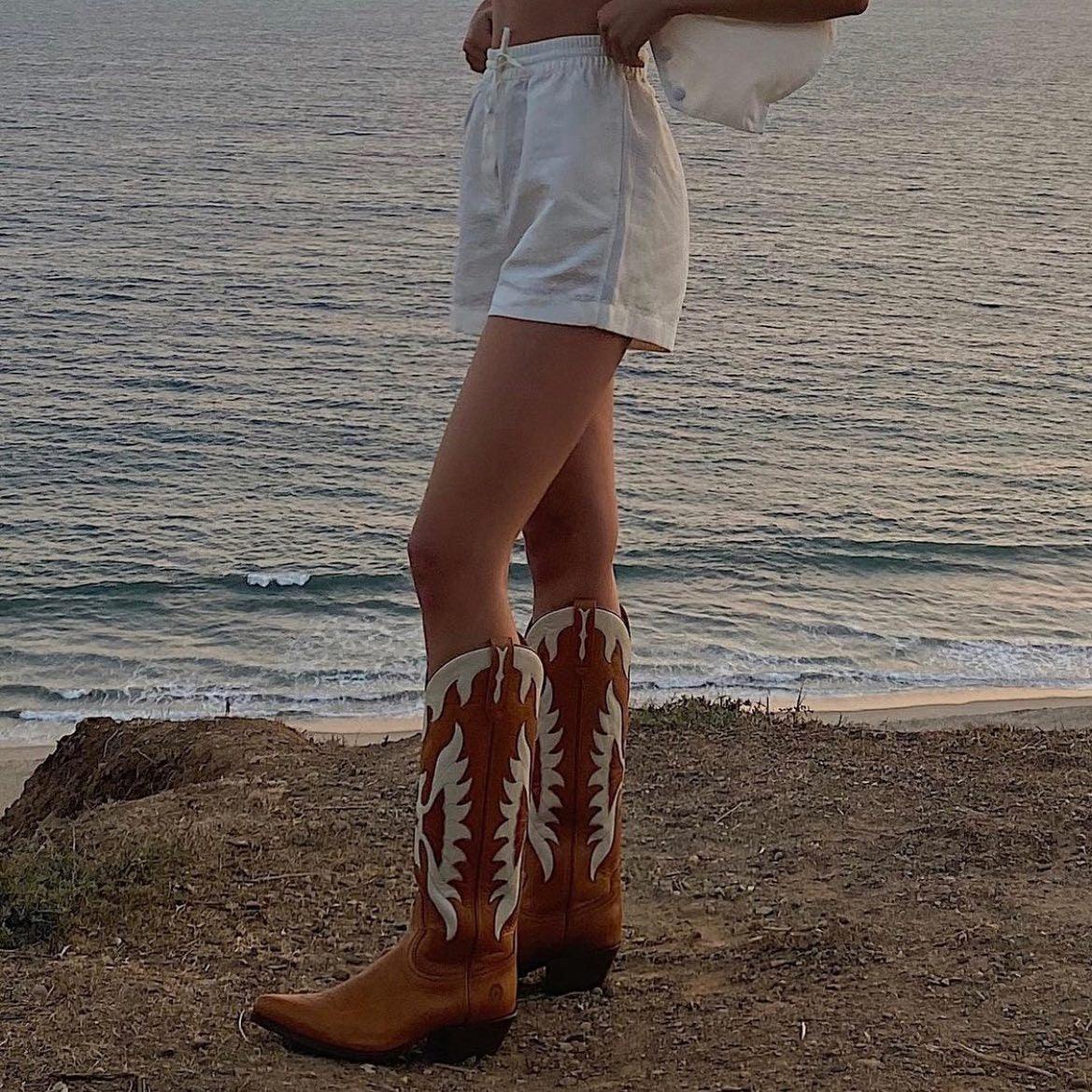 Woman wearing Rising Phoenix Cowgirl Boots - Stylish Cowboy Boots for Trendy Women near ocean view