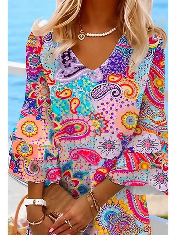 Woman wearing a Classic V-Neck Beach Dress with vibrant floral pattern and 3/4 sleeves near the ocean.