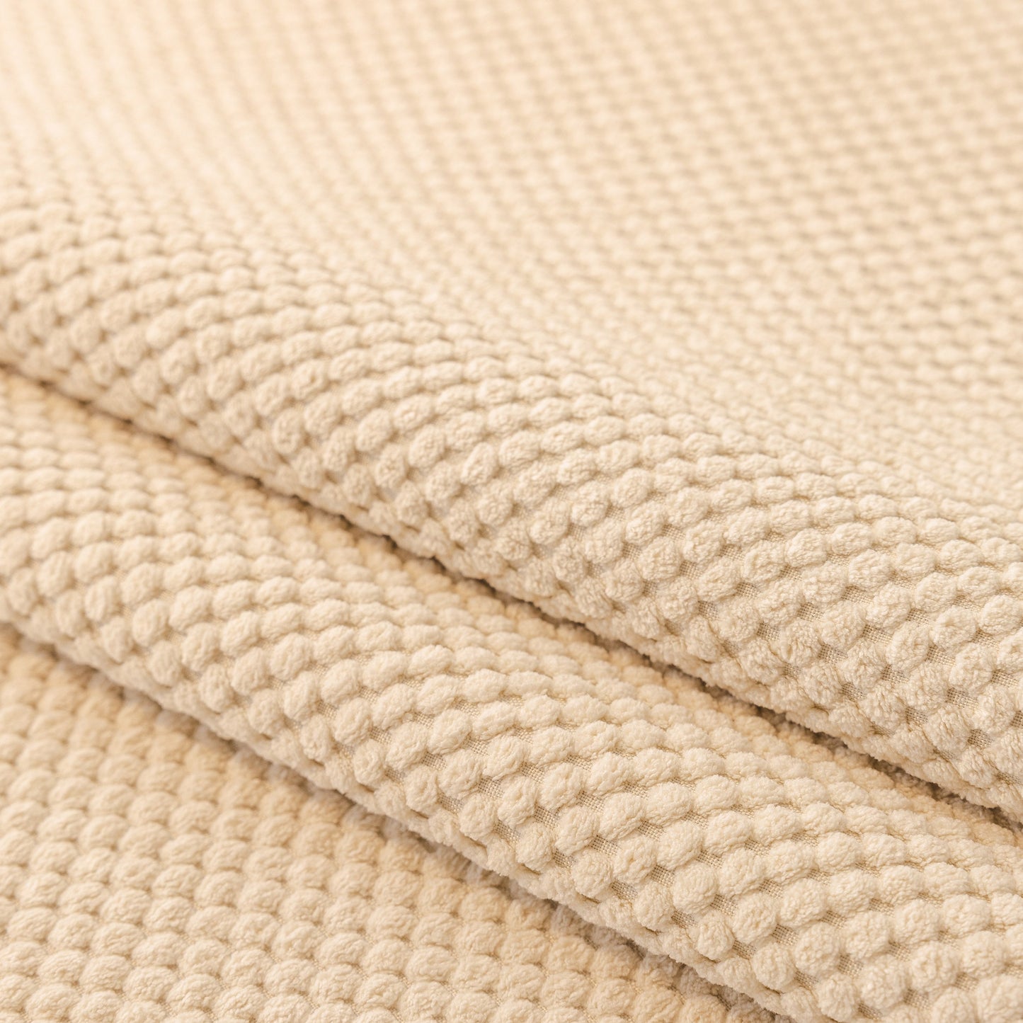 Close-up of the beige honeycomb texture on a Dog Washable Sofa Protector Cover, Non-Slip Couch Slipcover with Soft Furry Trim