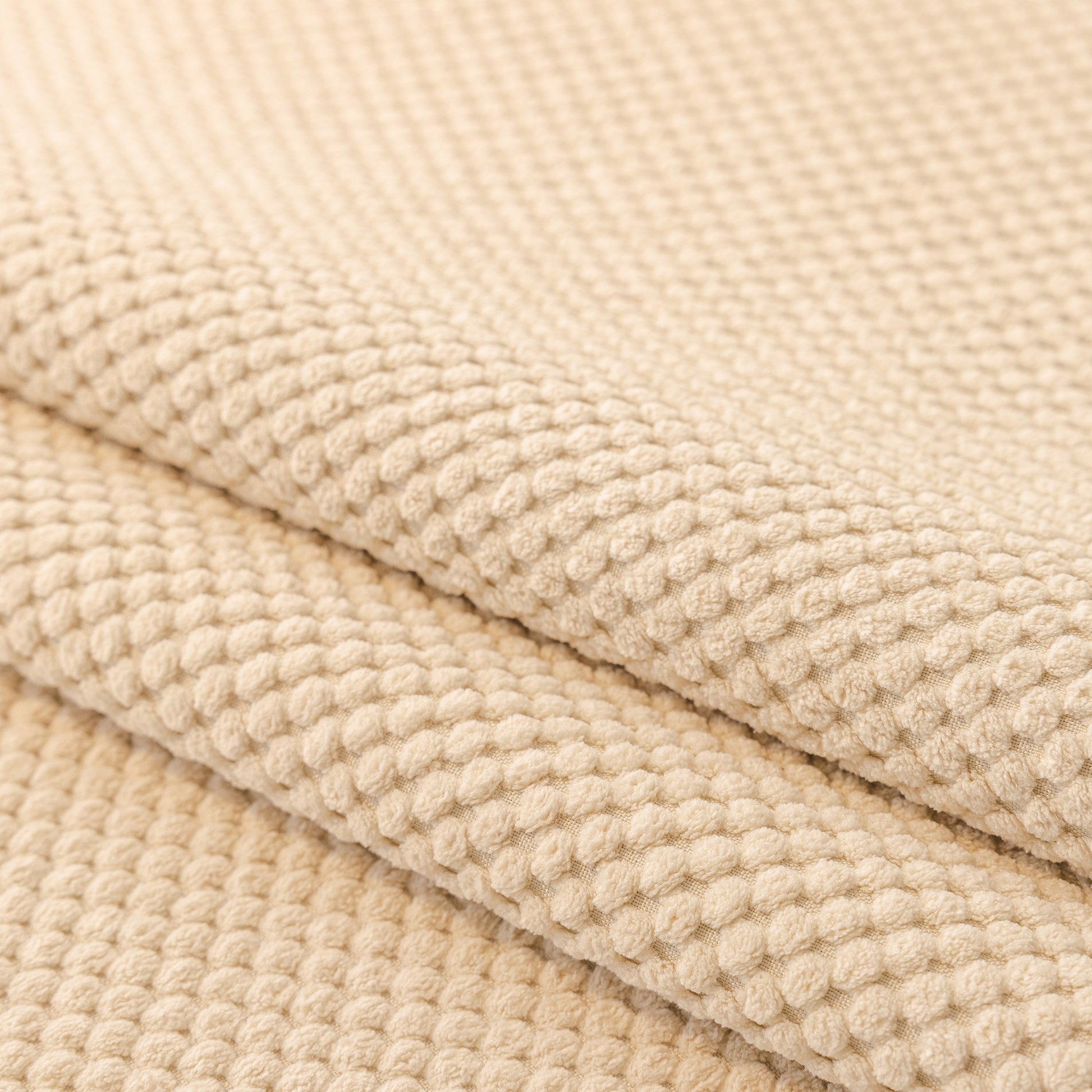 Close-up of the beige honeycomb texture on a Dog Washable Sofa Protector Cover, Non-Slip Couch Slipcover with Soft Furry Trim