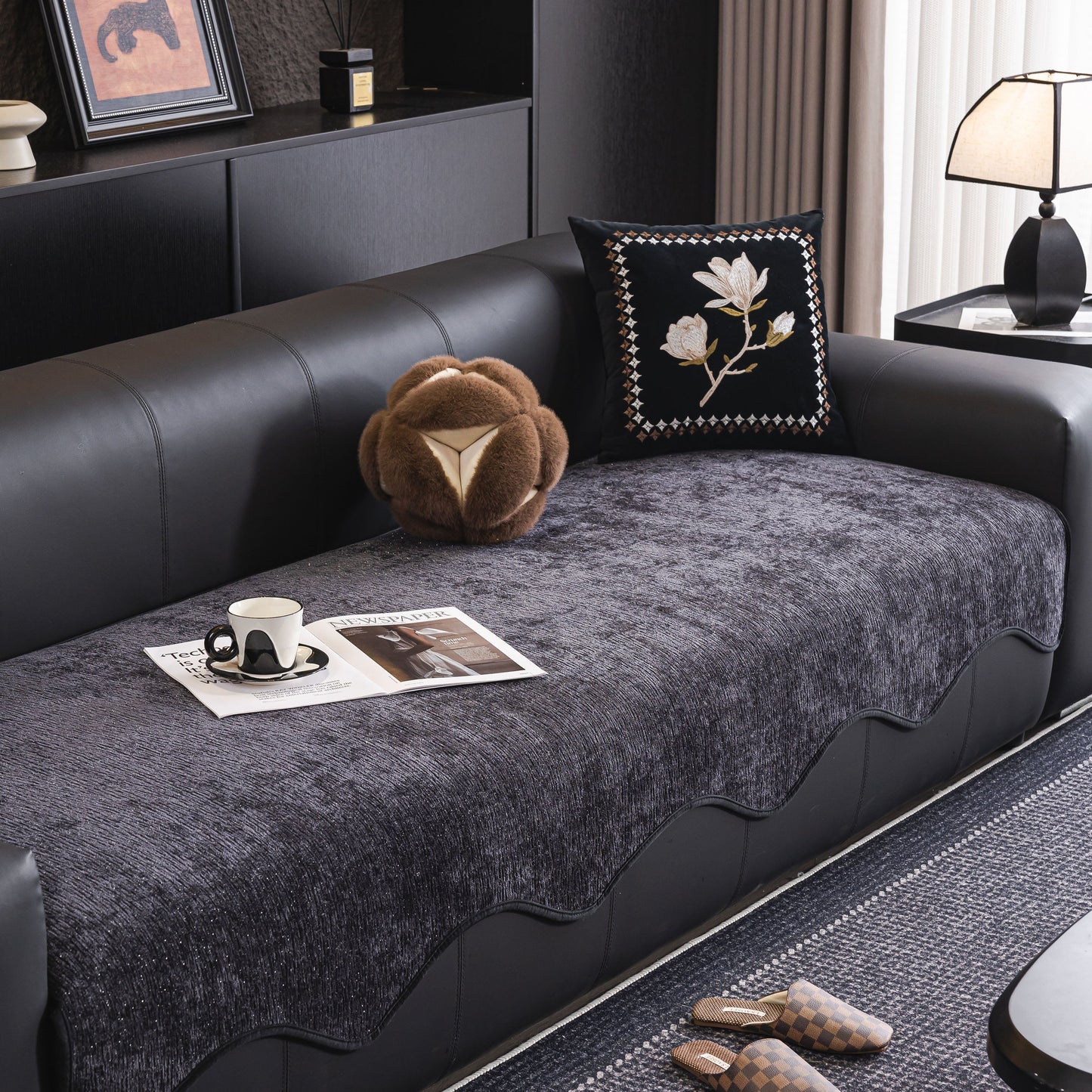 Chenille Couch Cover with Scalloped Edge, Non-Slip Modular Slipcover Sectional on a black leather sofa in an elegant living room.
