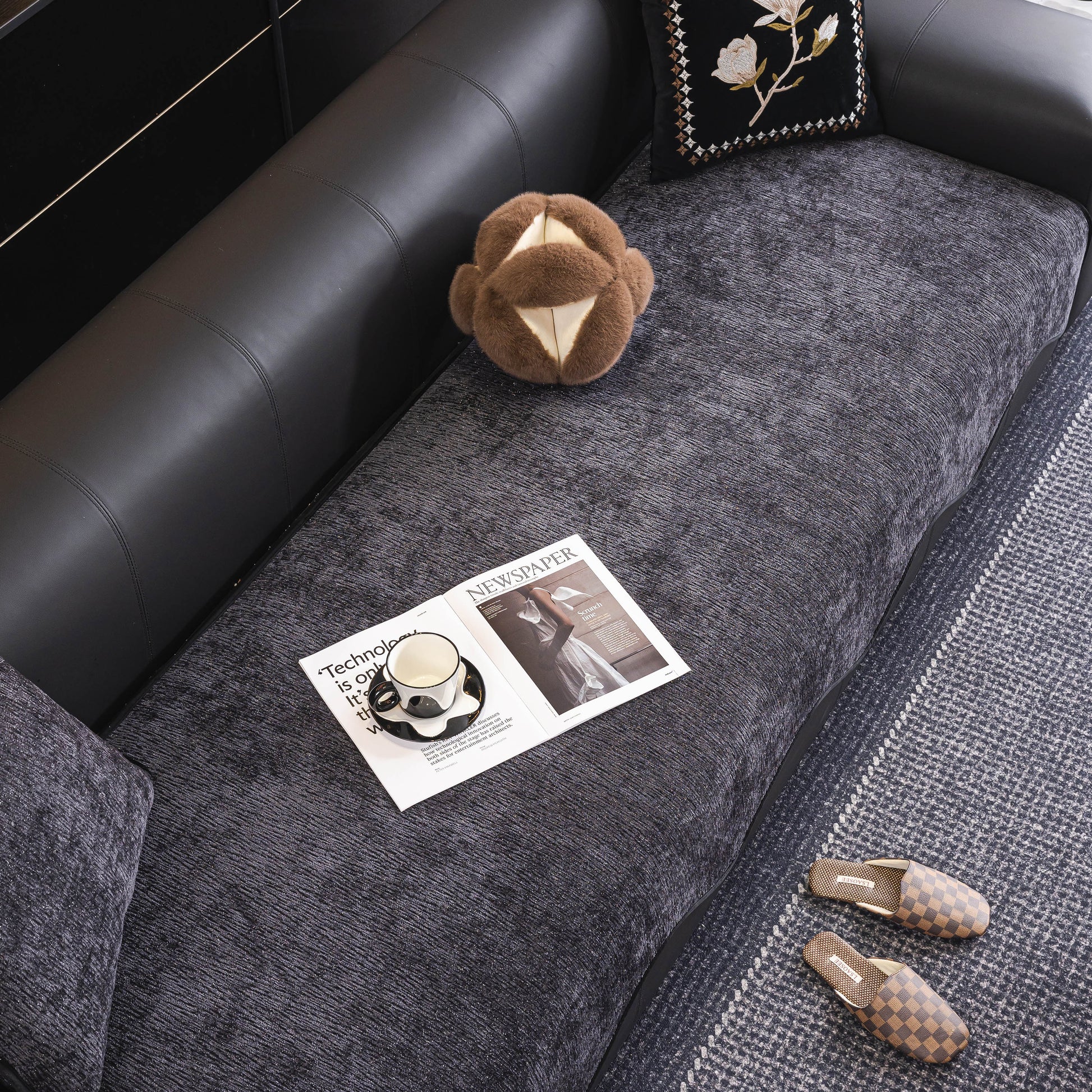 Chenille Couch Cover with Scalloped Edge, Non-Slip Modular Slipcover Sectional on a leather sofa with slippers and a magazine on top.
