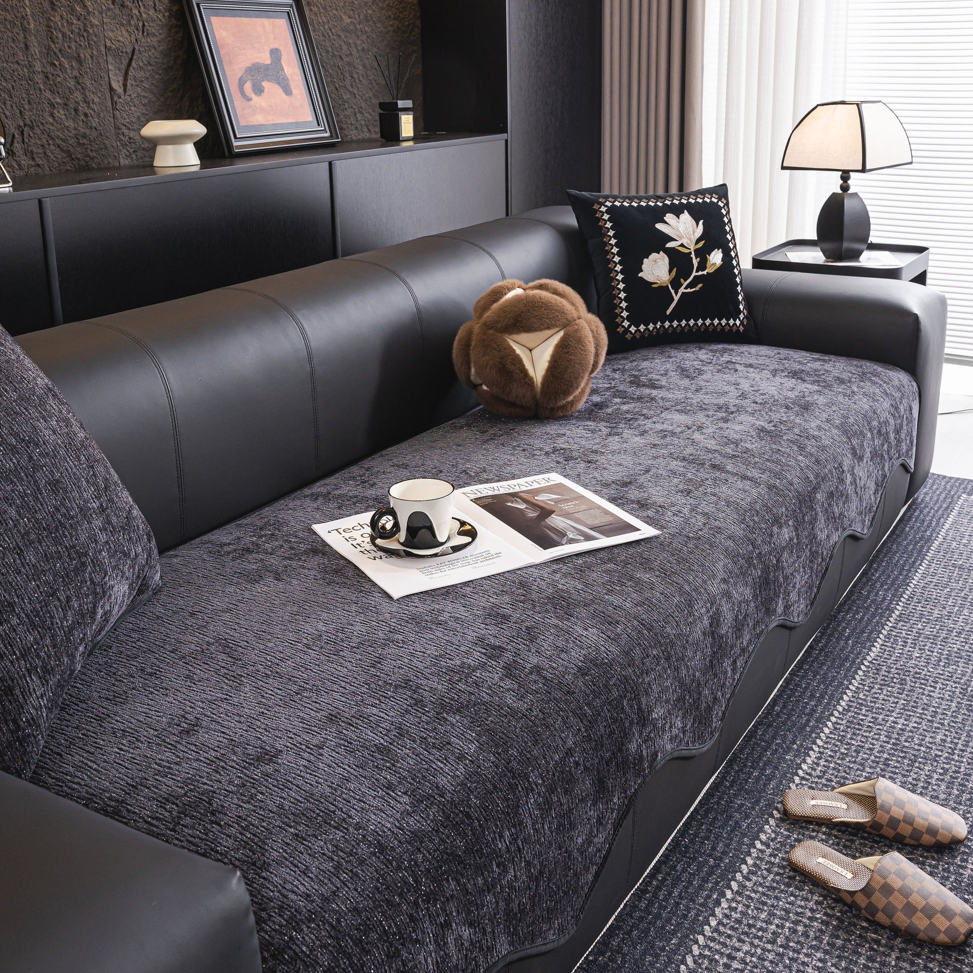 Gray Chenille Couch Cover with Scalloped Edge, Non-Slip Modular Slipcover Sectional on a black leather sofa in a modern living room.